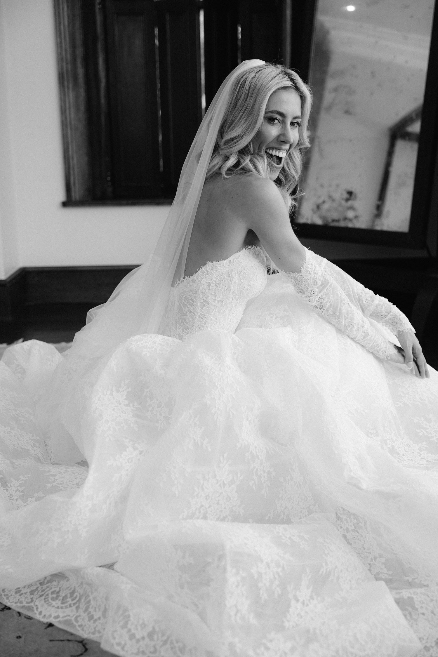 Black and white portrait of someone in an elaborate wedding gown with veil.