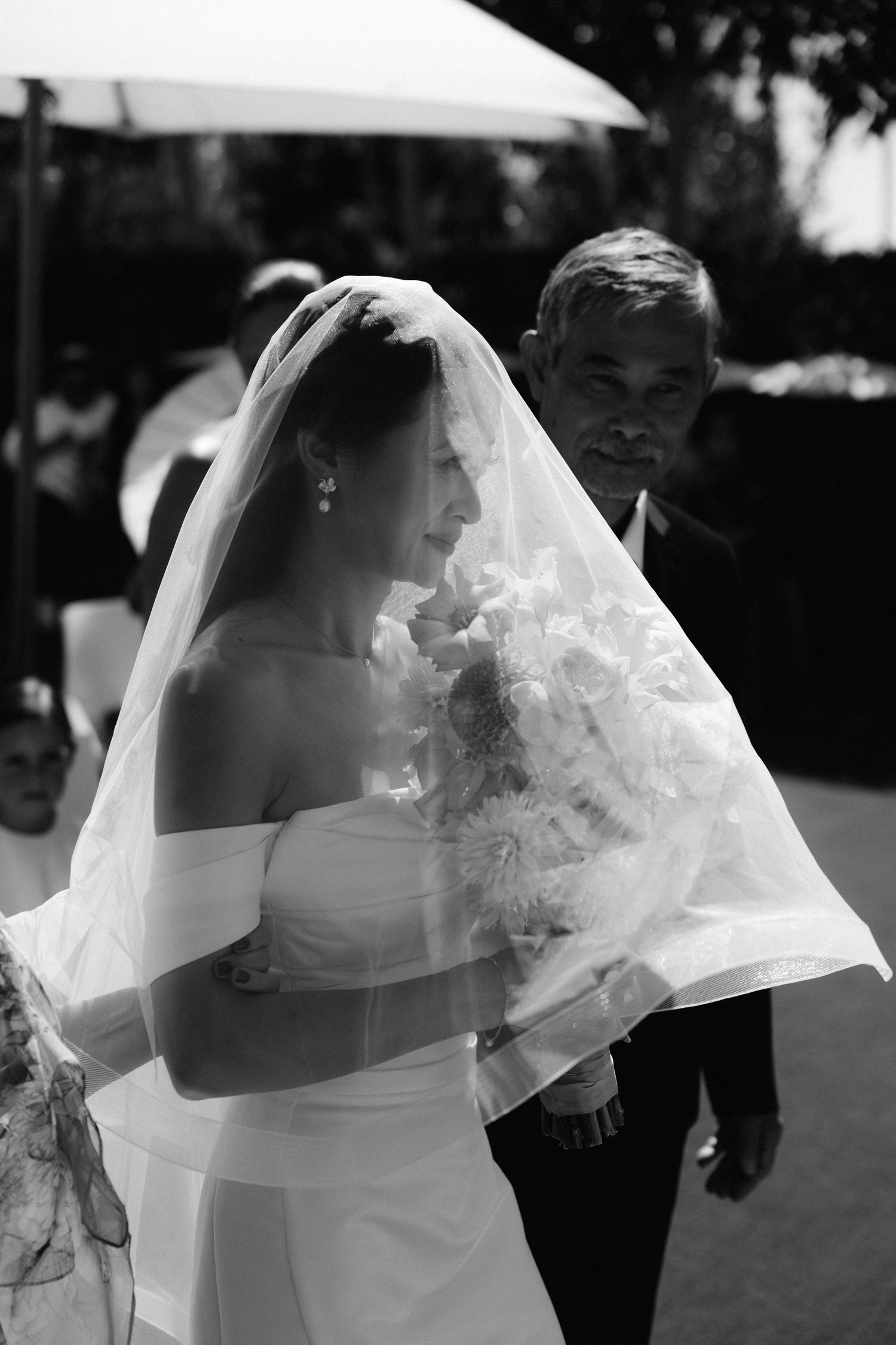 A series of black and white wedding photos showing a bride in a veil and white dress from different angles outdoors.