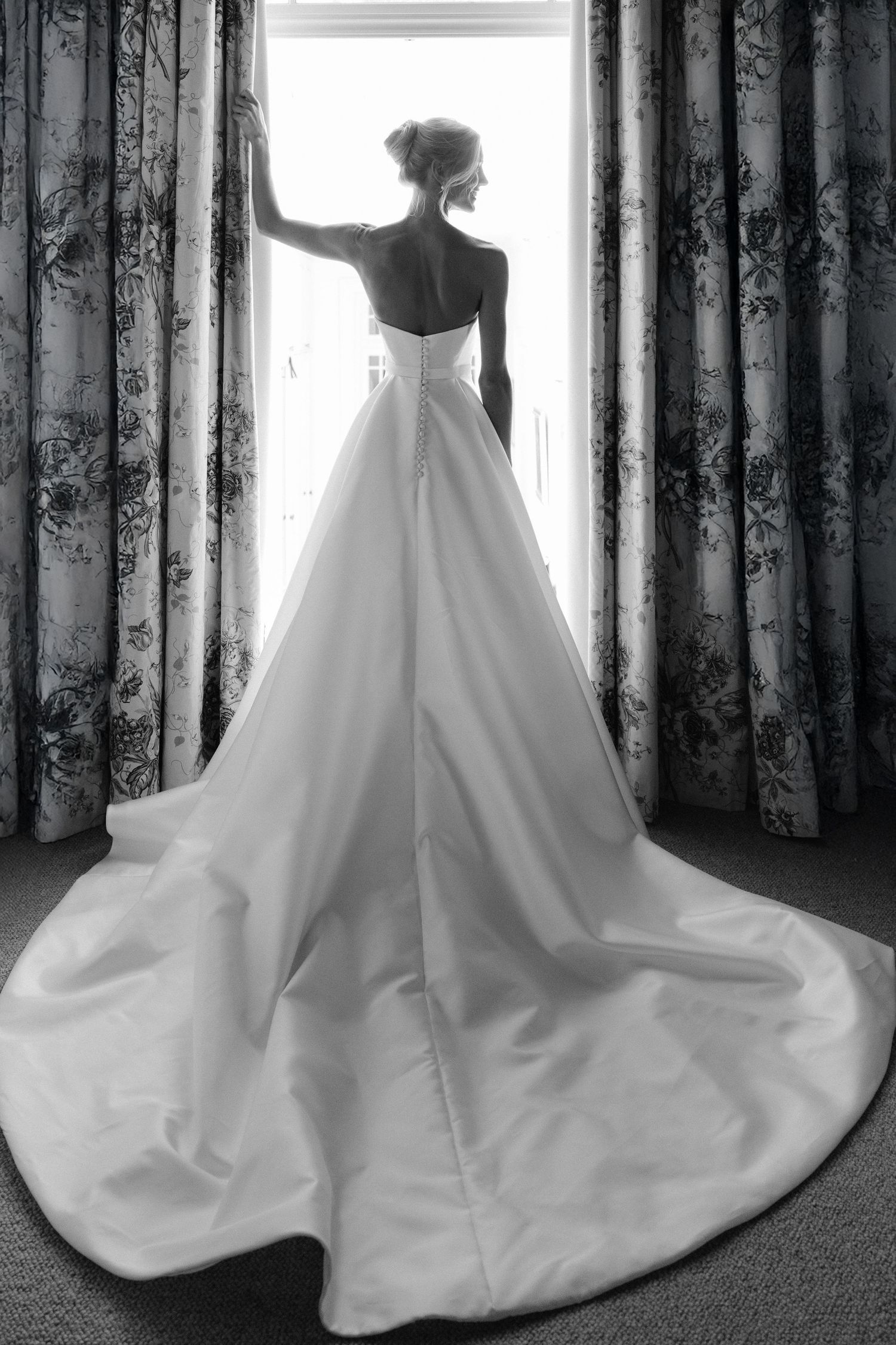 A series of black and white photos showing the elegant flow of a white wedding dress train against dark curtains.