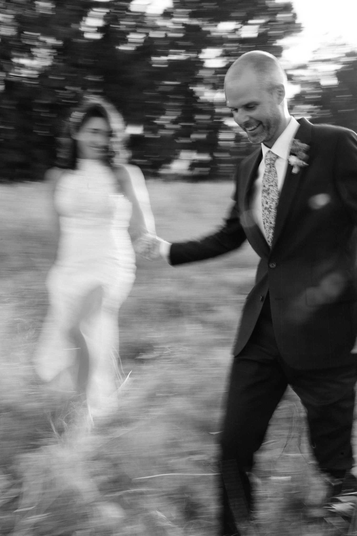 A blurred black and white motion sequence shows a couple dancing outdoors in wedding attire.