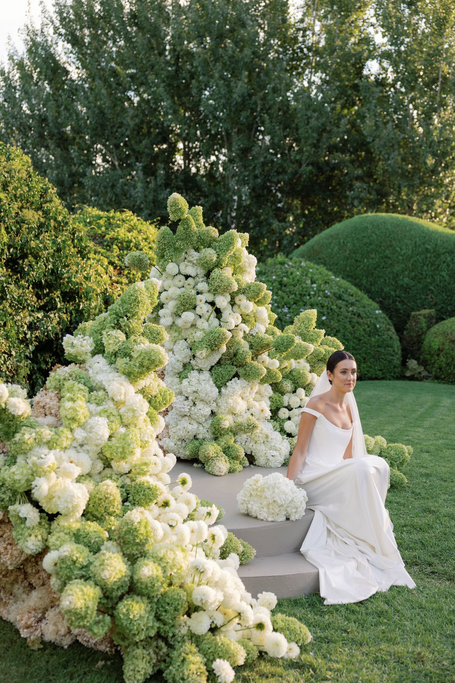 A series of outdoor photos featuring white hydrangea flowers and flowing white fabric against a lush green lawn.