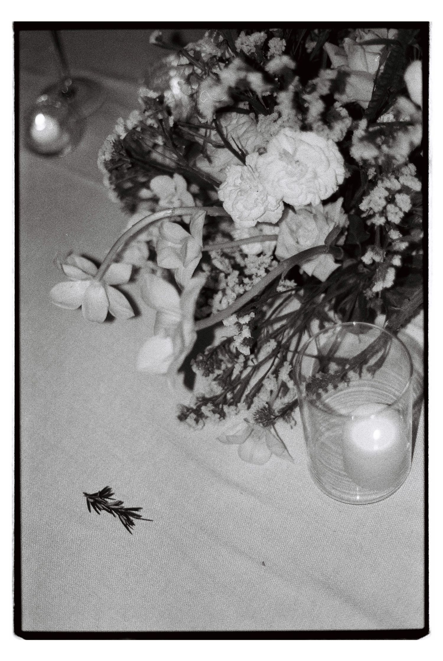 Black and white photo of wedding floral centerpiece with candlelight on a table.