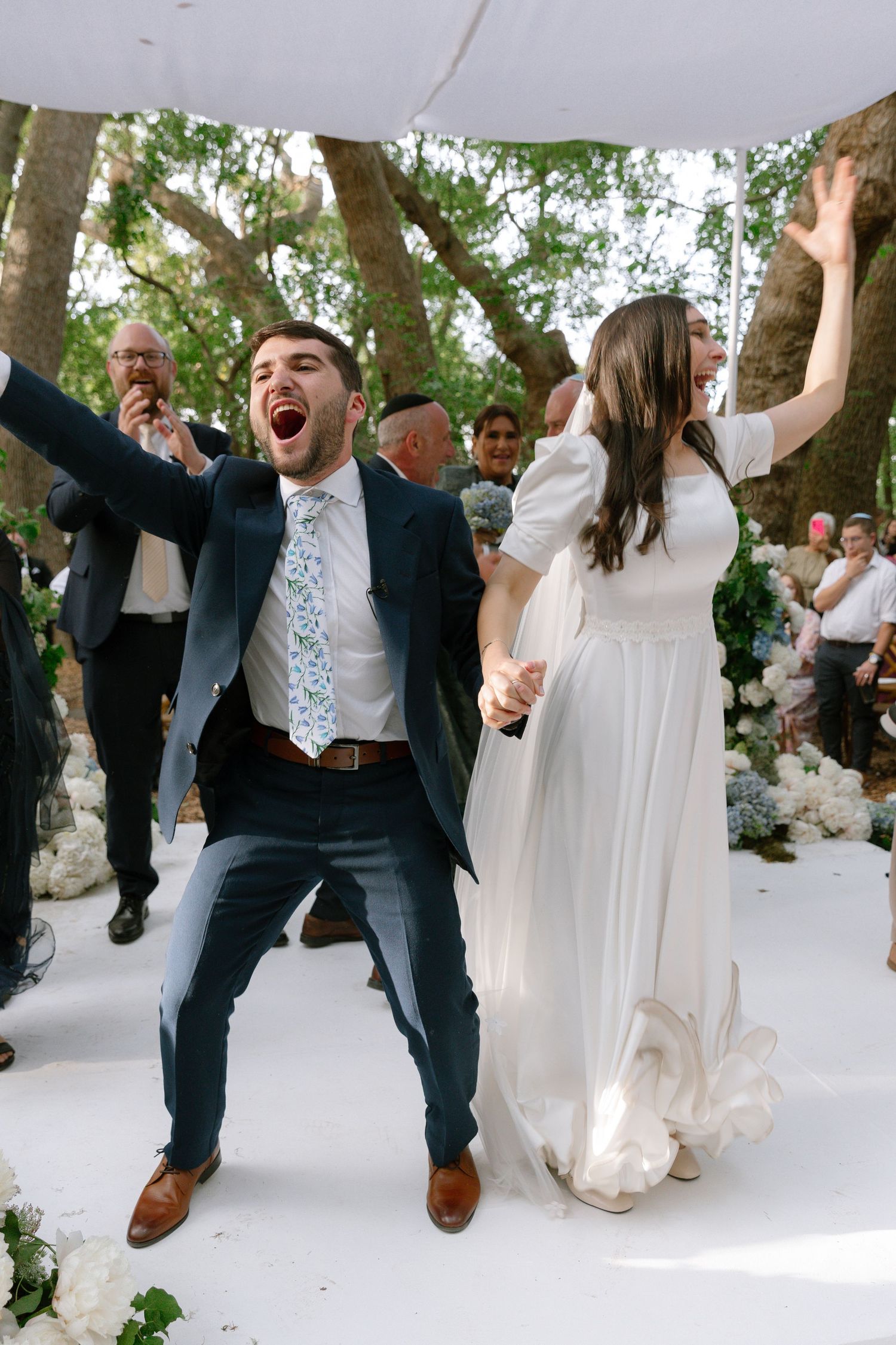 Wedding celebration sequence showing joyful dancing and jumping moments in white and black formal attire.