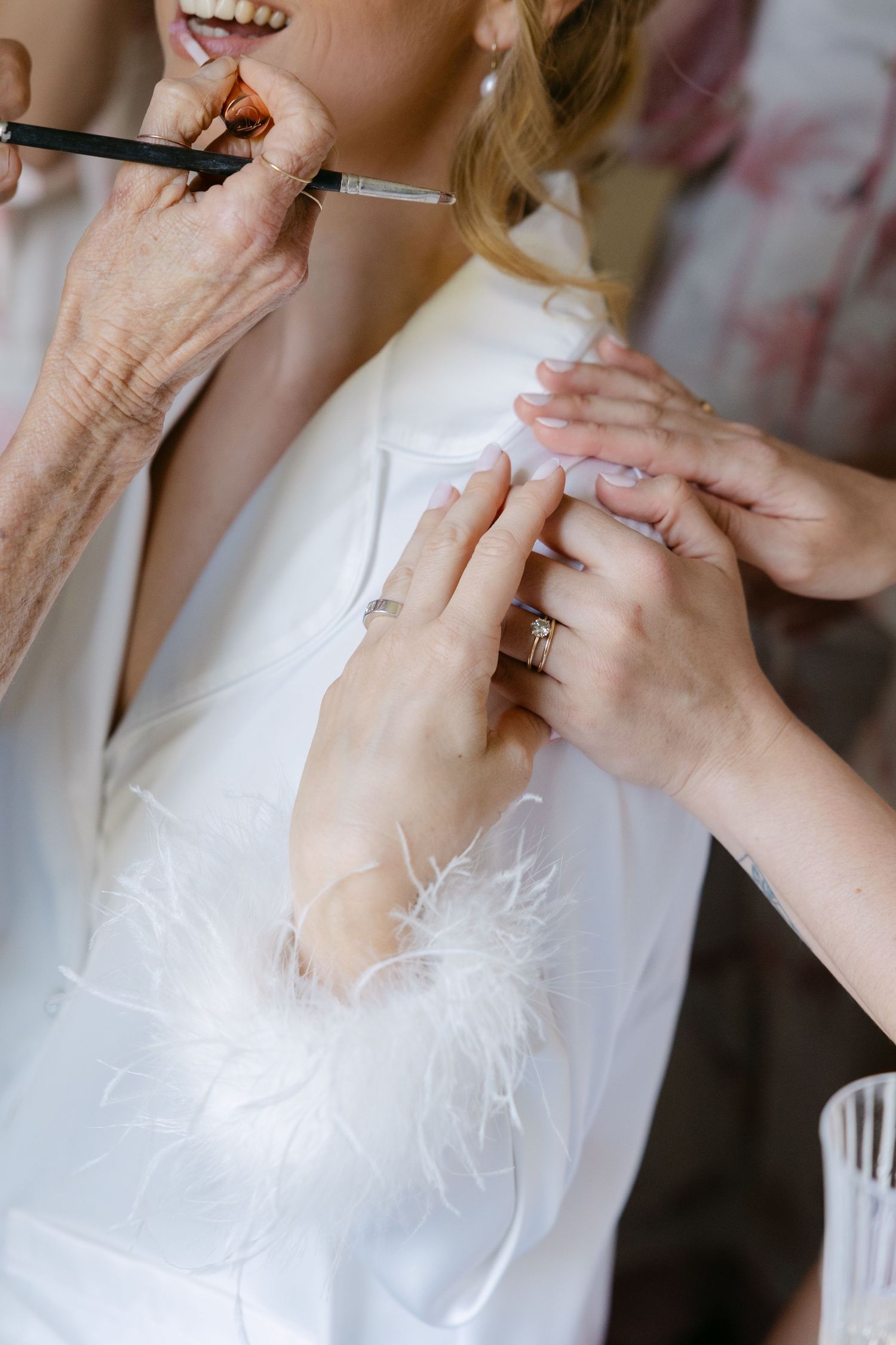 Close-up shots show hands adjusting and fastening buttons on a white wedding dress during bridal preparation.