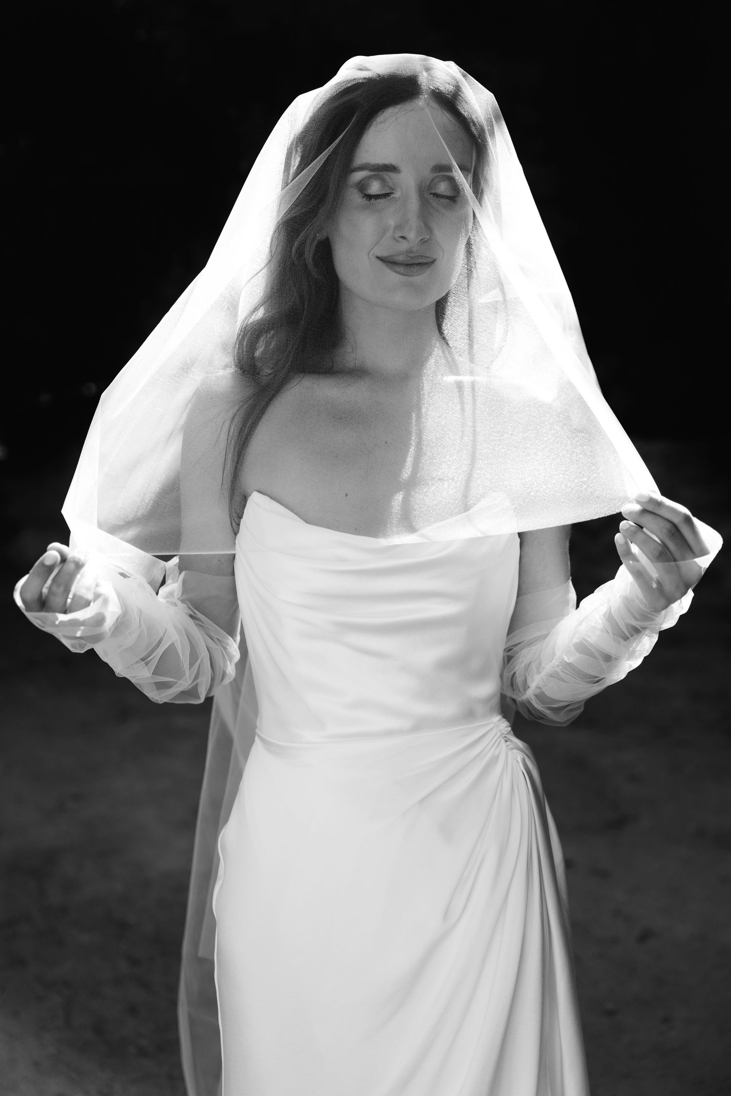 A sequence of black and white portraits showing a bride adjusting her flowing white veil against a dark background.