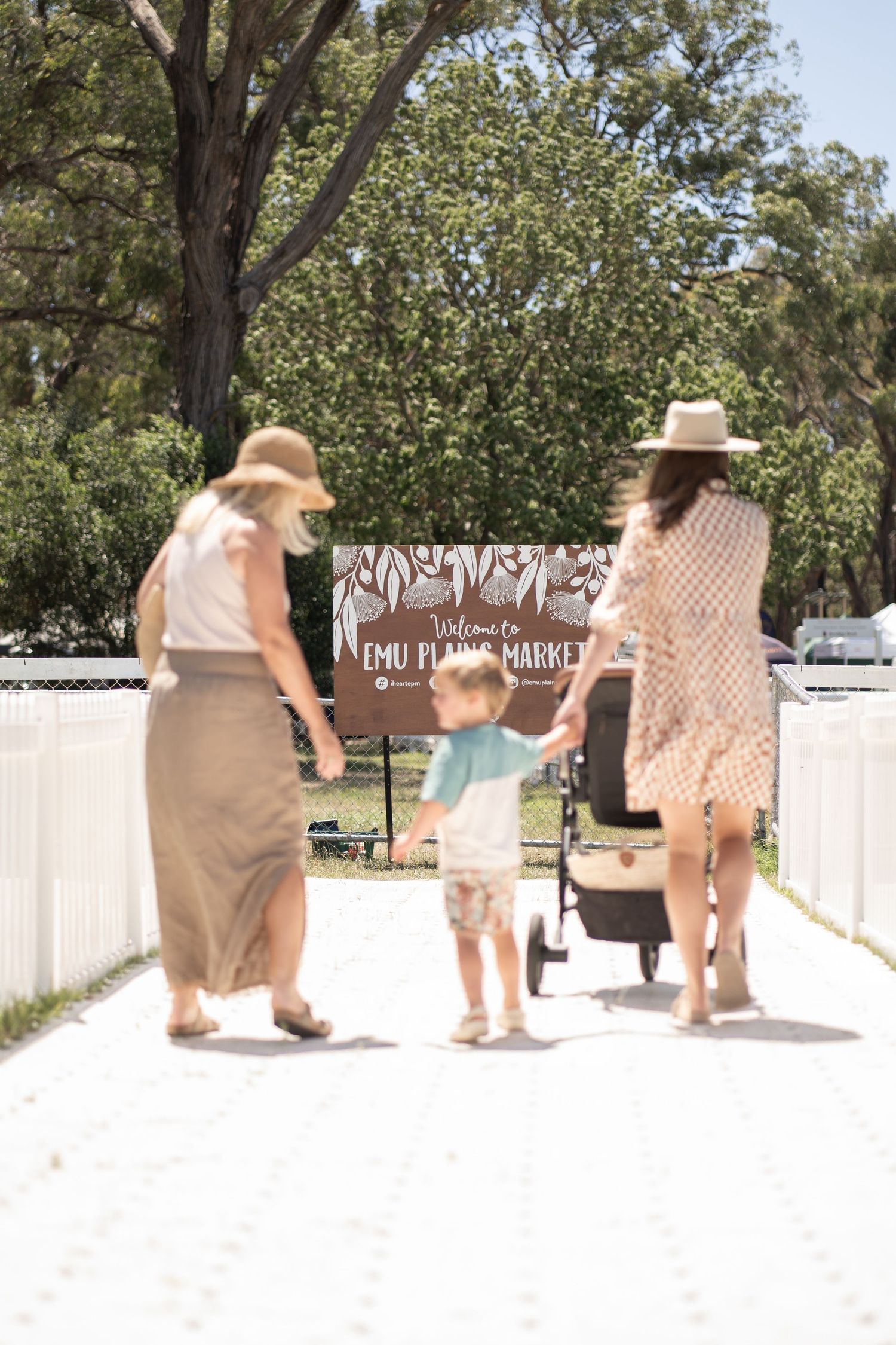 A charming scene of people walking down a white pathway at an outdoor market or event.