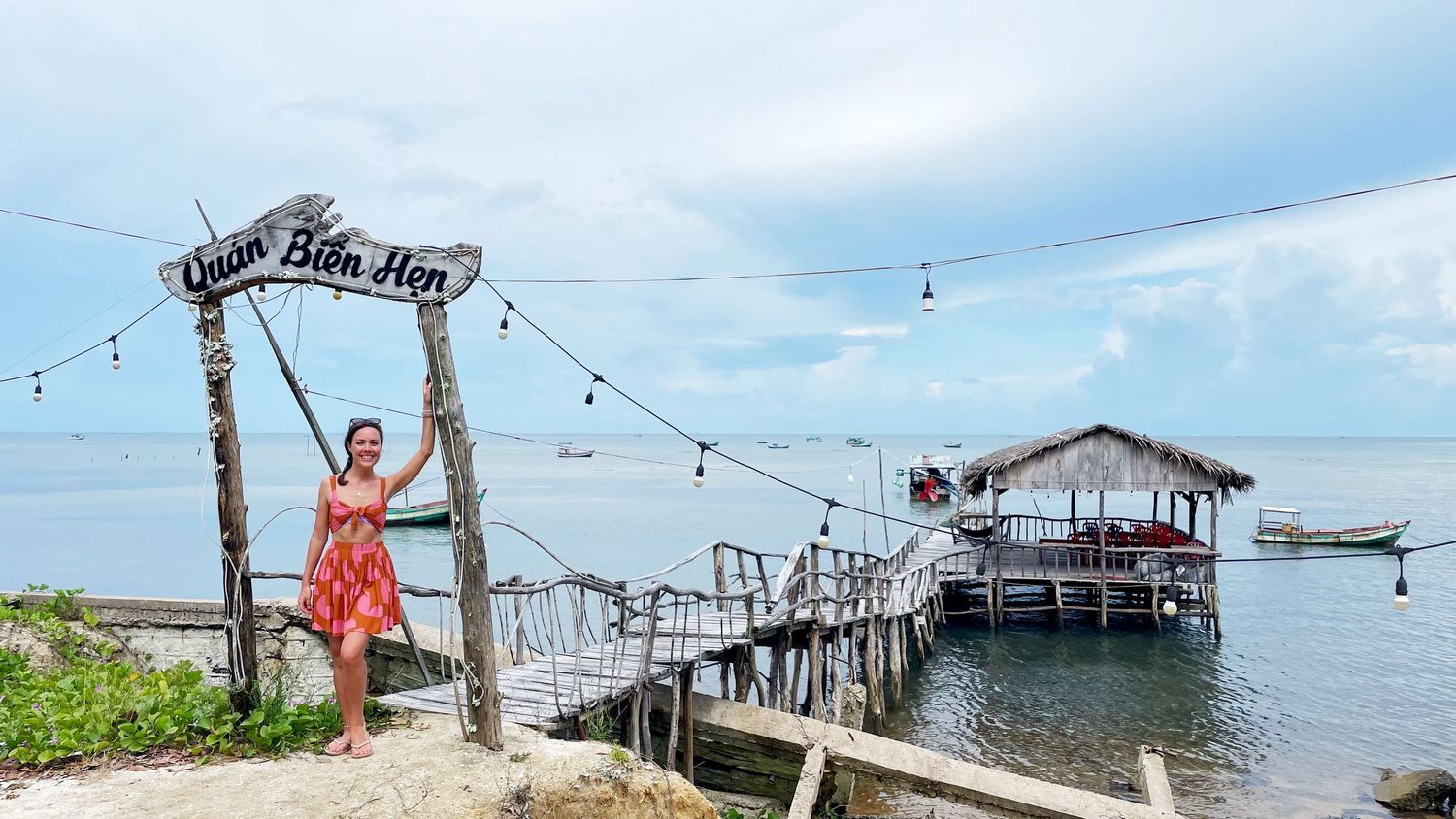 Wooden pier and stilt house decorated with string lights overlooking turquoise waters.