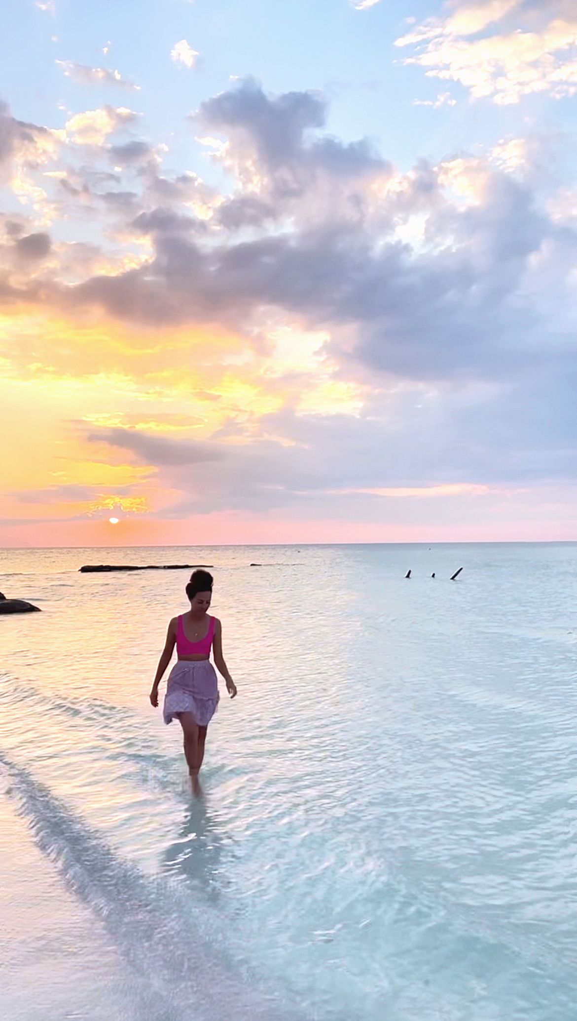 Peaceful beach scene with calm waters reflecting a colorful sunset sky.
