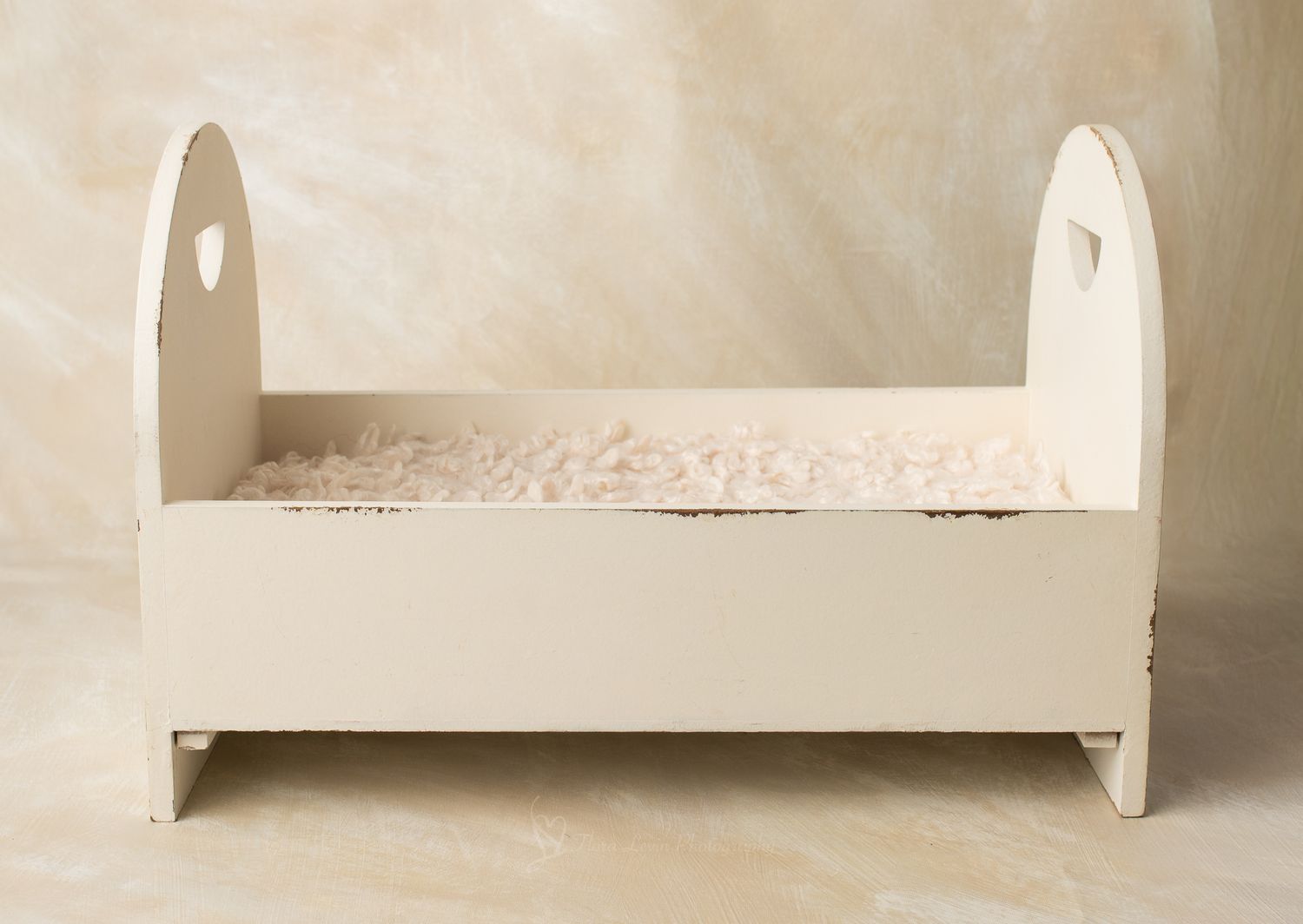 Vintage white wooden  bed with heart cutouts and fluffy lace mattress on beige background.