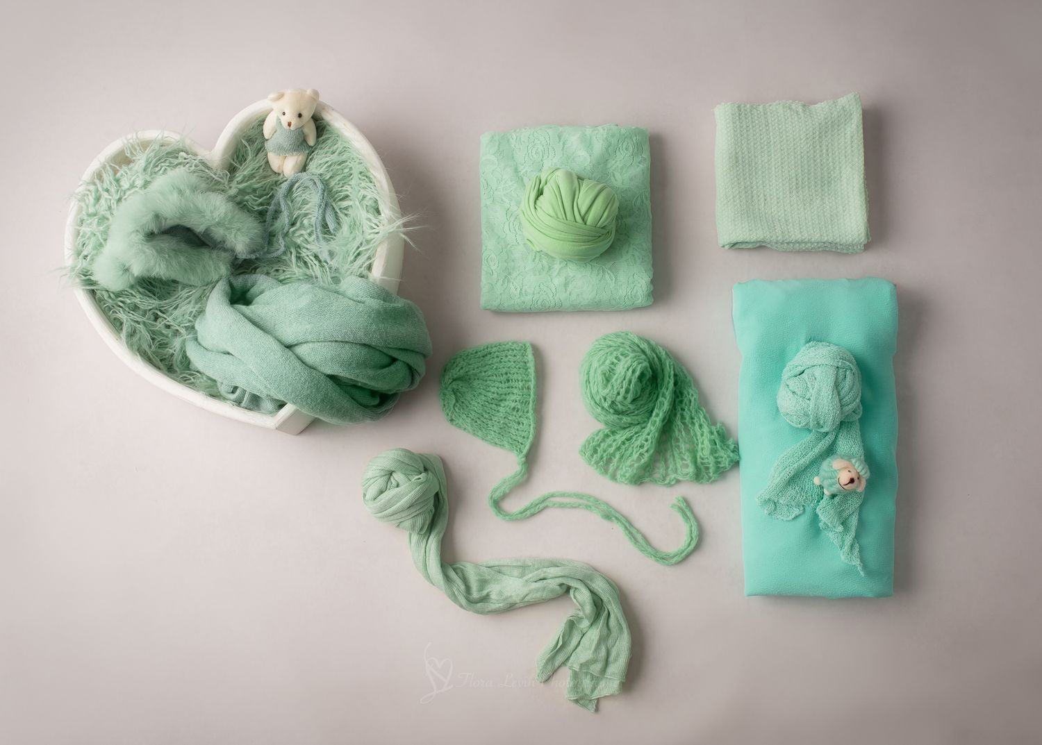Mint green newborn photography props set including wraps, knit bonnet, yarn, and accessories arranged on white background.
