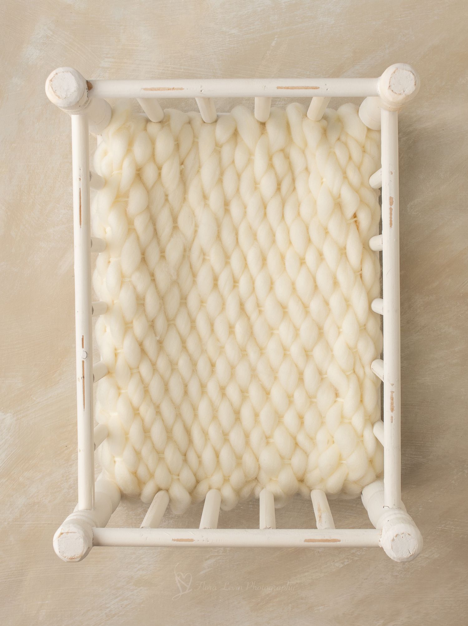 White wooden baby crib with spindle rails and cream mattress, perfect for newborn photography props