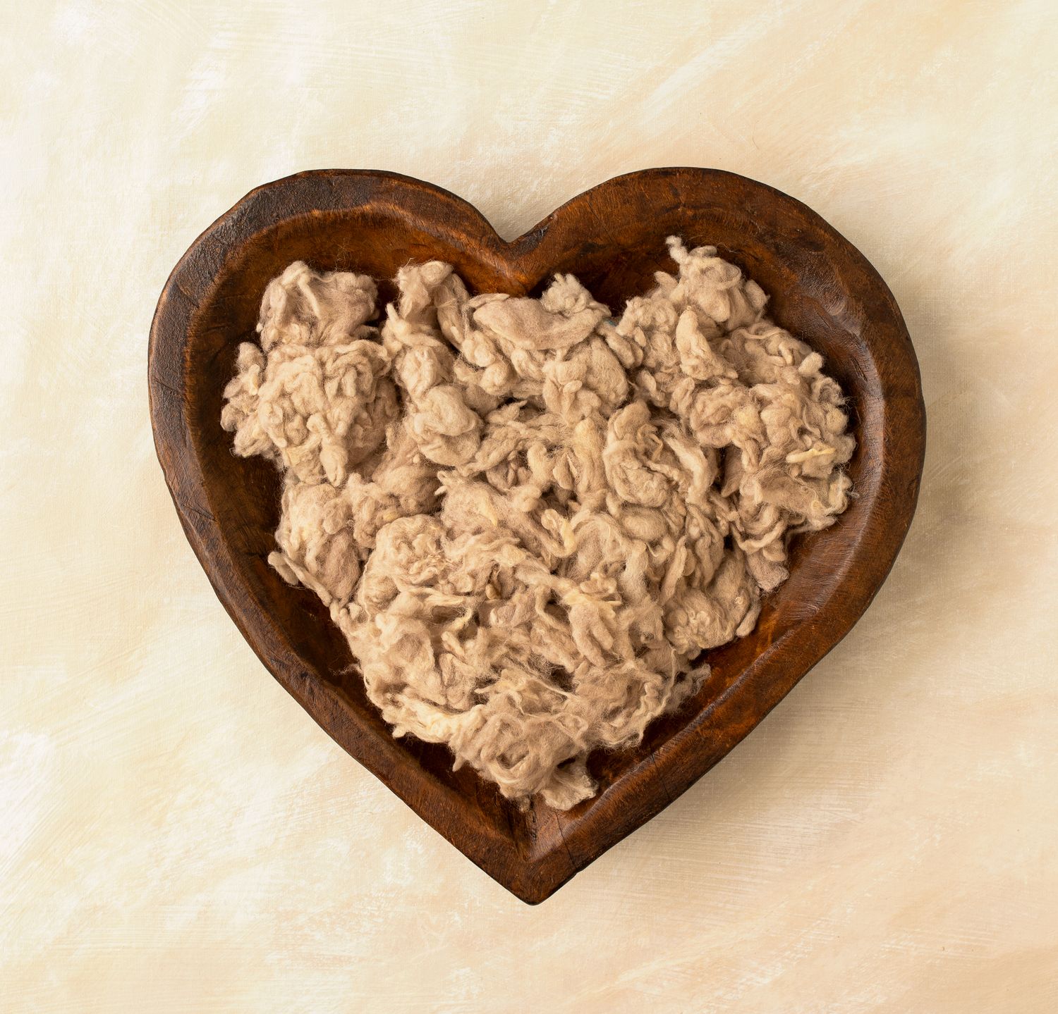 heart-shaped wooden bowl on a marble surface.