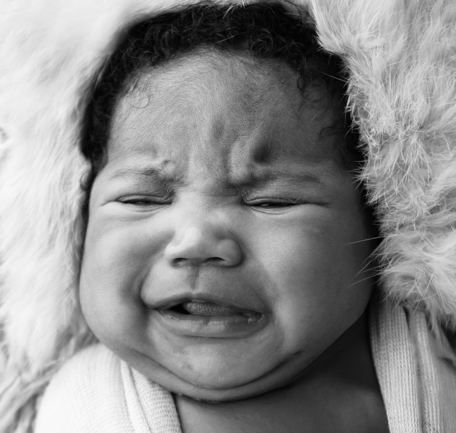 baby girl wrap in fur crying . Black and white photography