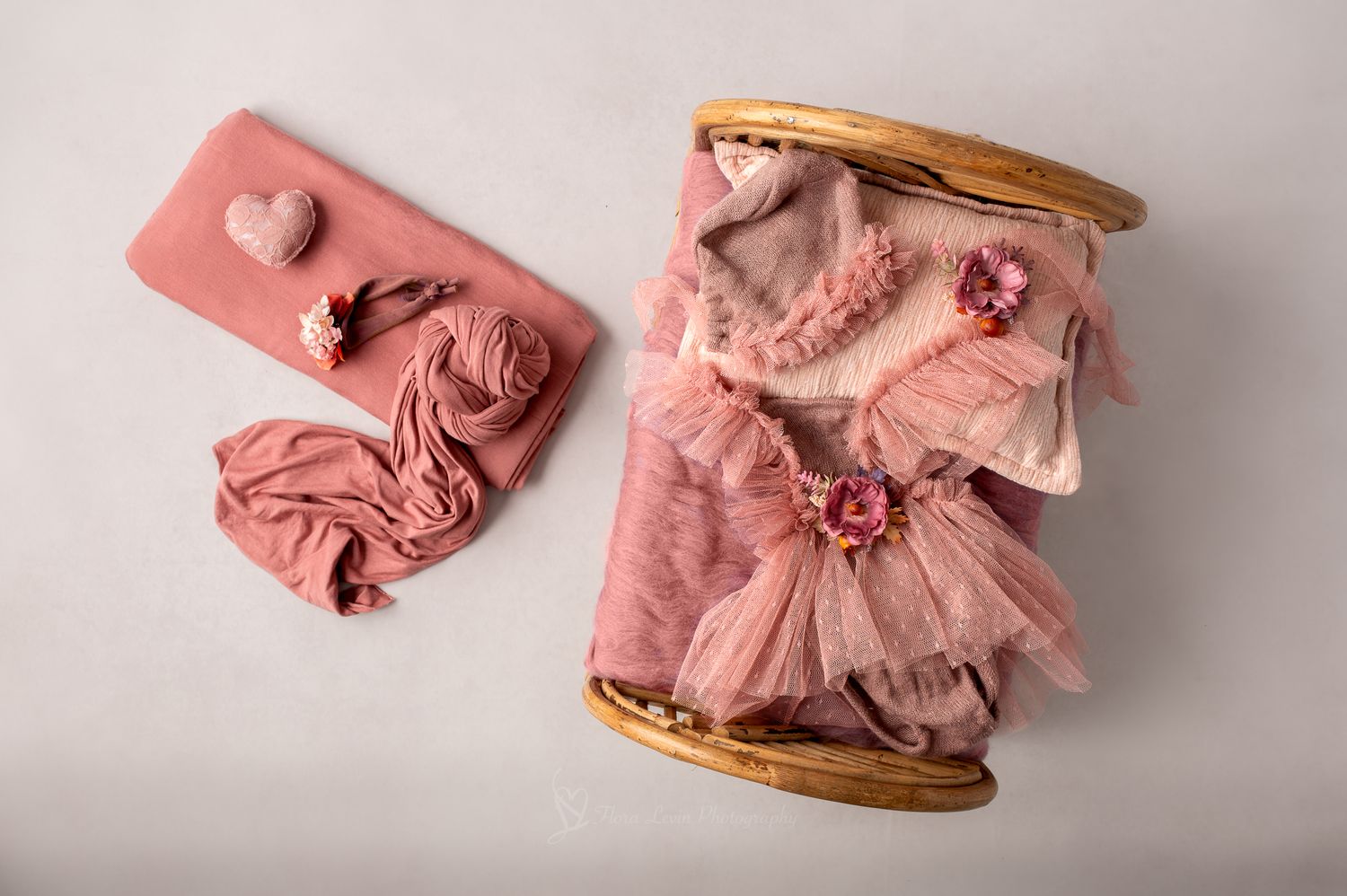 Mauve newborn photography props including tulle dress, floral headband, wrap, and wooden bed on white background.
