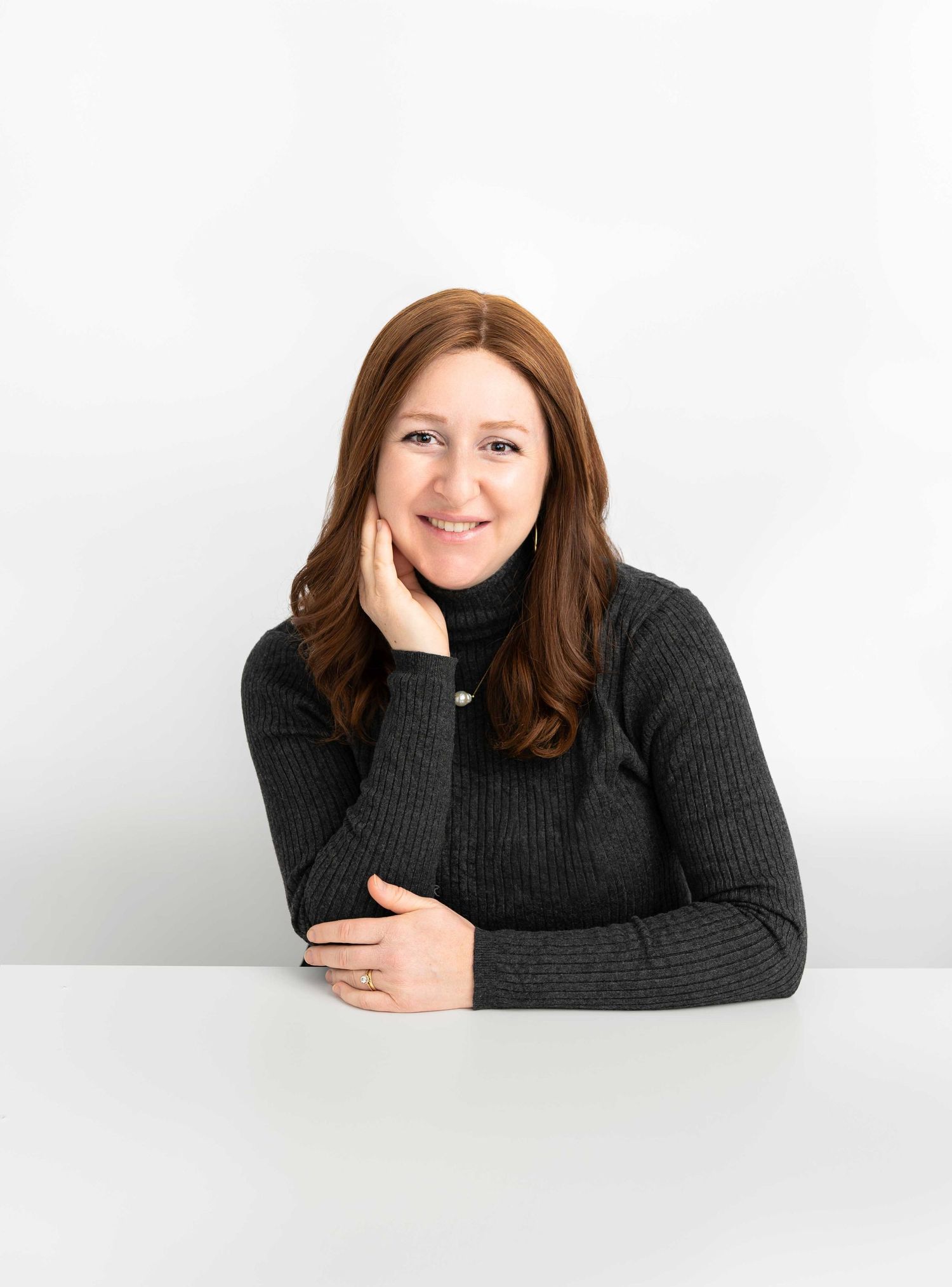 Women in a black sweater poses against a white background in a headshot session in Philadelphia.
