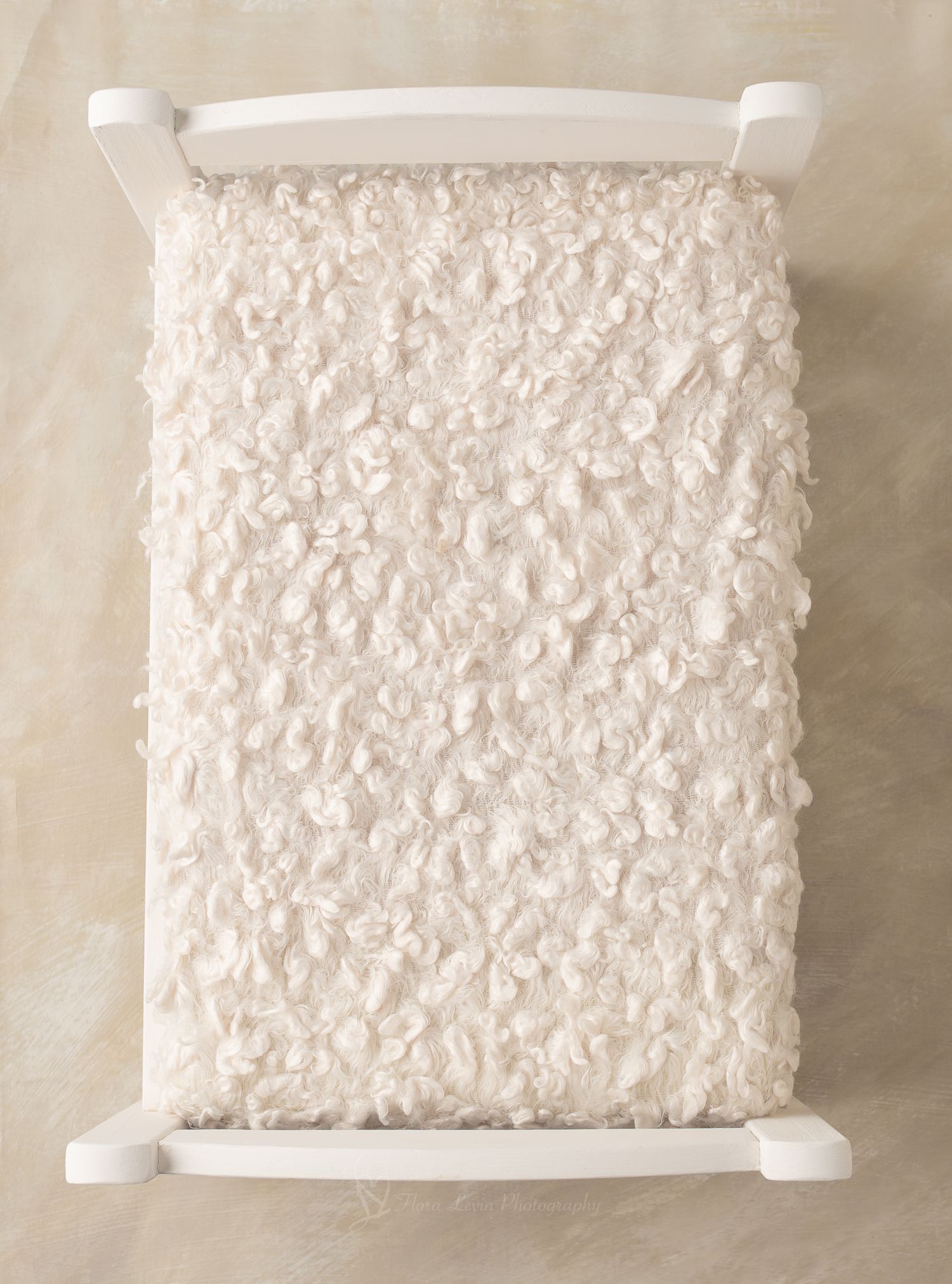 White wooden  bed with fluffy ivory faux fur mattress, perfect for newborn photography props.
