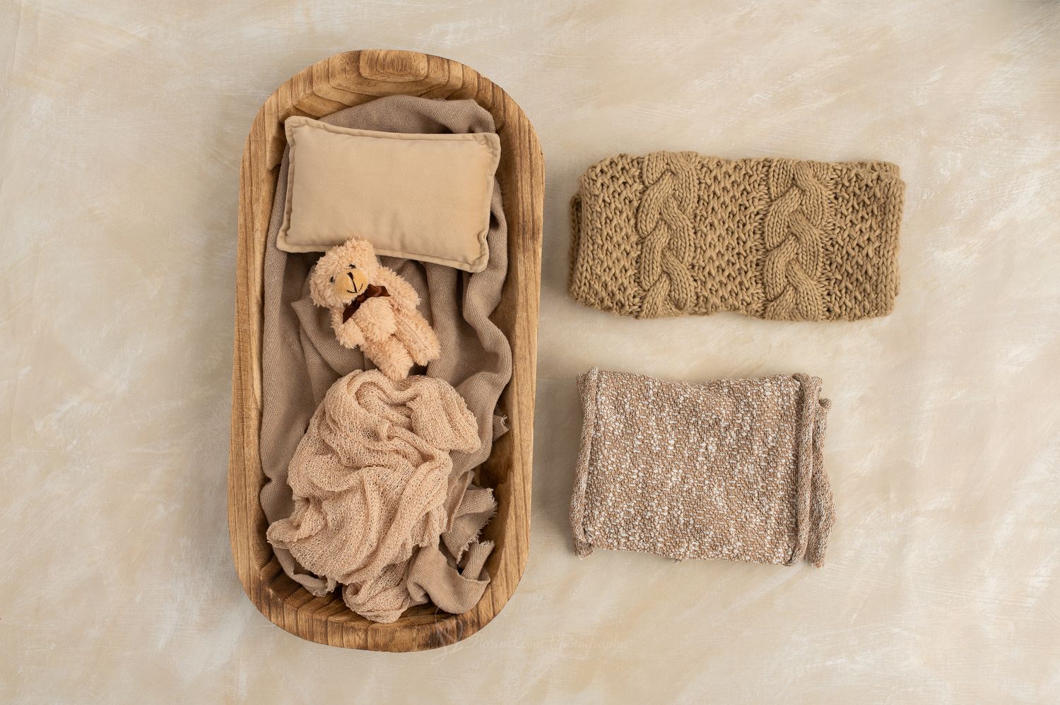 Oval bowl, neutral color pillow, neutral color bear, neutral wrap with beige wraps and knit textiles on a neutral background.