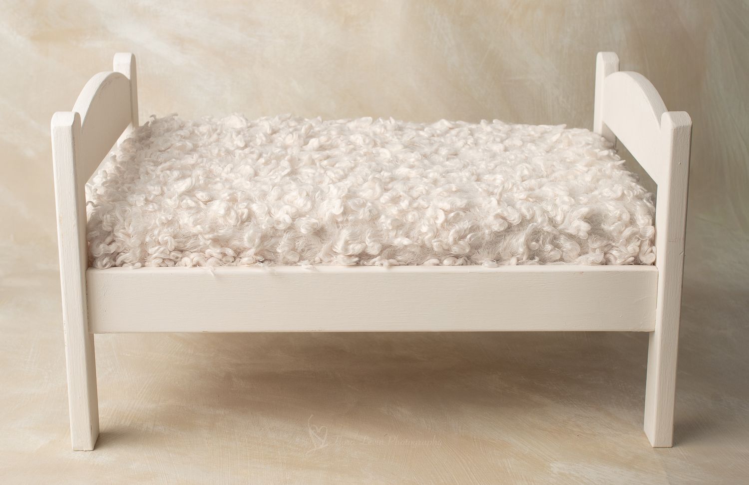 White wooden  bed with fluffy ivory faux fur mattress, perfect for newborn photography props.