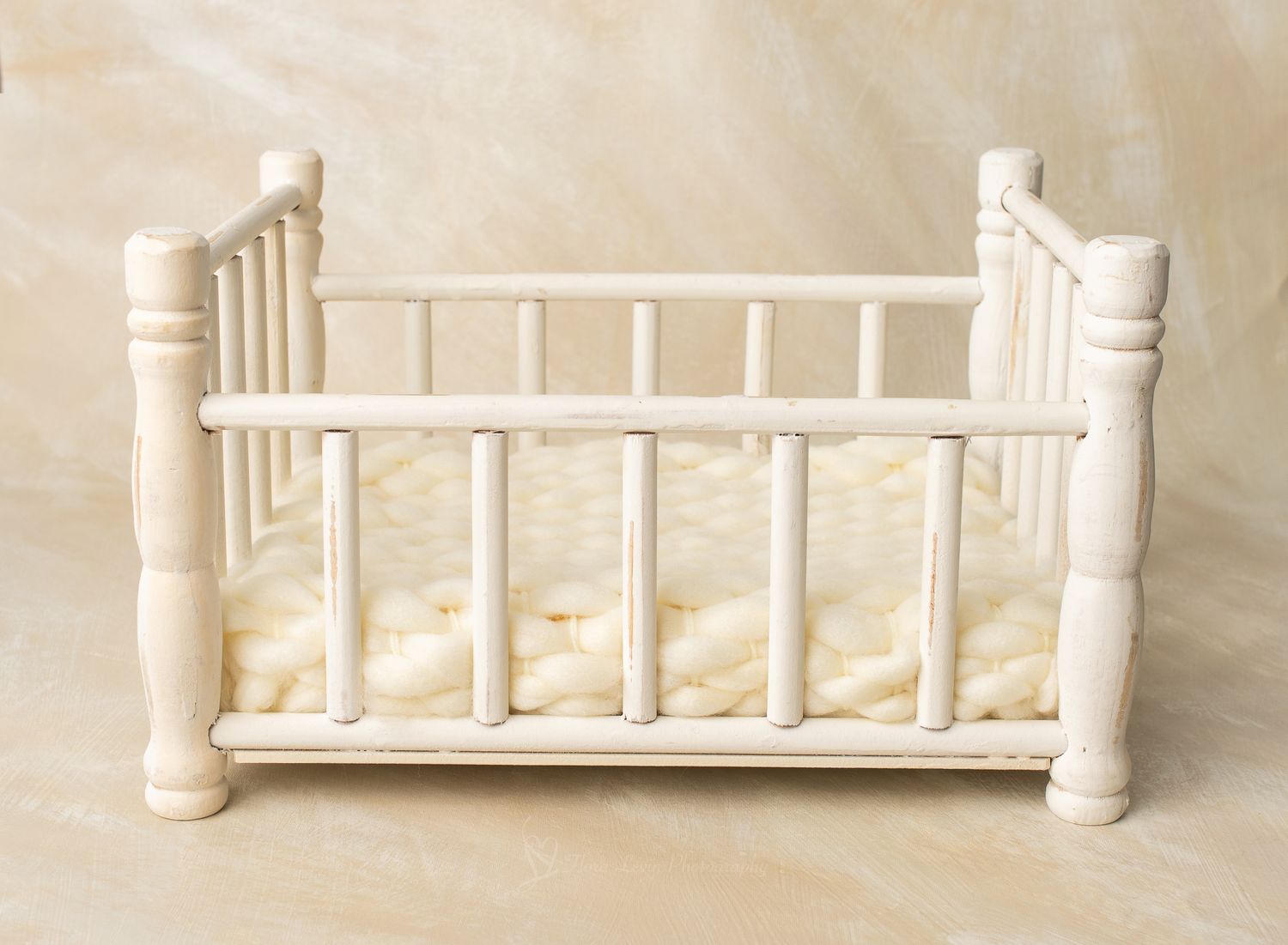White wooden baby crib with spindle rails and cream mattress, perfect for newborn photography props