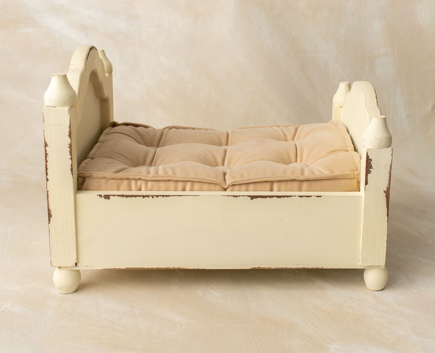 Cream woodenbed with tufted beige cushion mattress, perfect for newborn photography