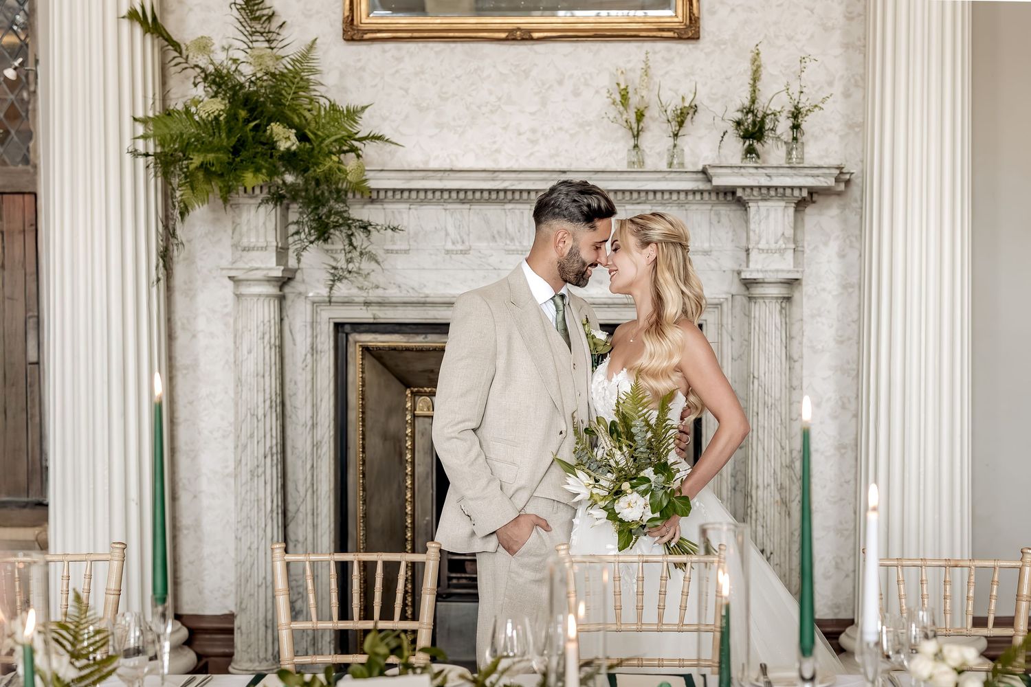 Elegant wedding couple kissing in a luxurious white room with classical architecture and decor.