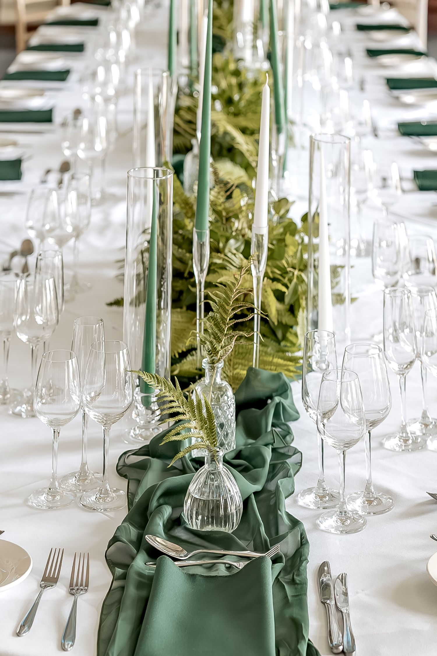 Elegant table setting with crystal glassware and emerald green napkins arranged in a row for formal dining.