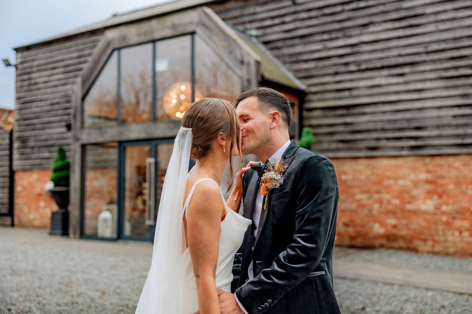 Newly weds share a romantic moment in front of a rustic wooden barn during their wedding day.