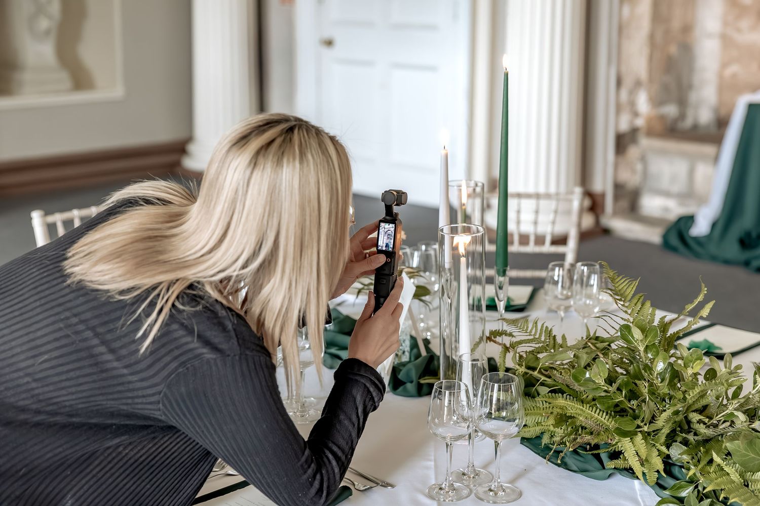Table settings with elegant glassware and greenery garland decorations at an upscale dining event, being video