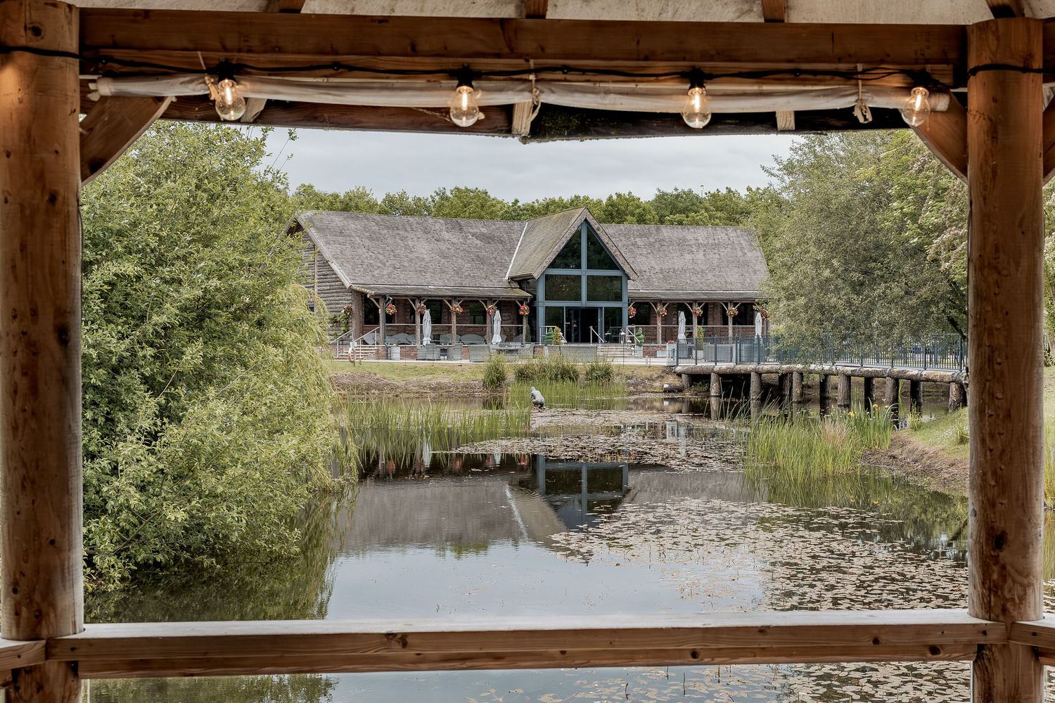 Wooden deck overlooking a serene pond with lily pads and traditional Japanese architecture in the background.