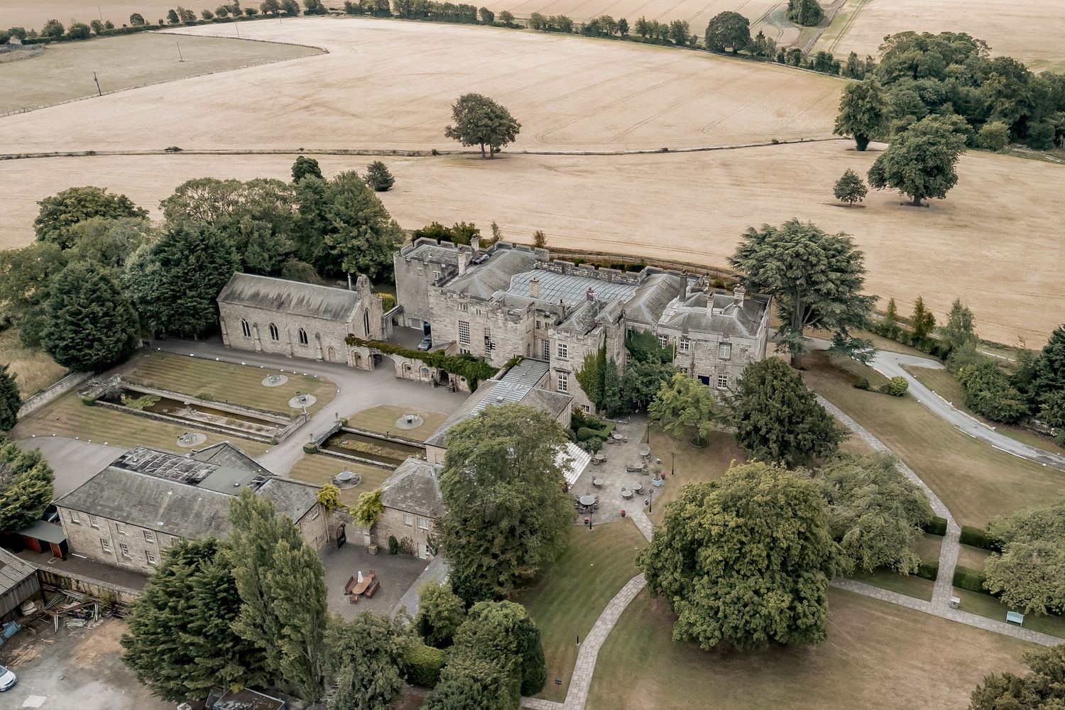 Aerial view of a historic stone castle with surrounding grounds and pathways in the countryside of Yorkshire.