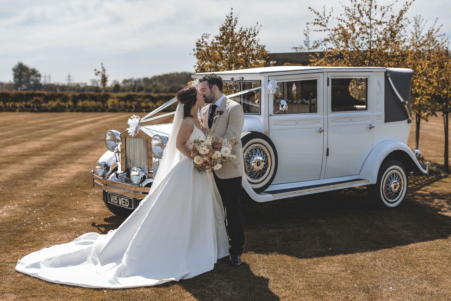 Natural couple kiss moment in front of their wedding transportation captured by a documentary wedding photographer.