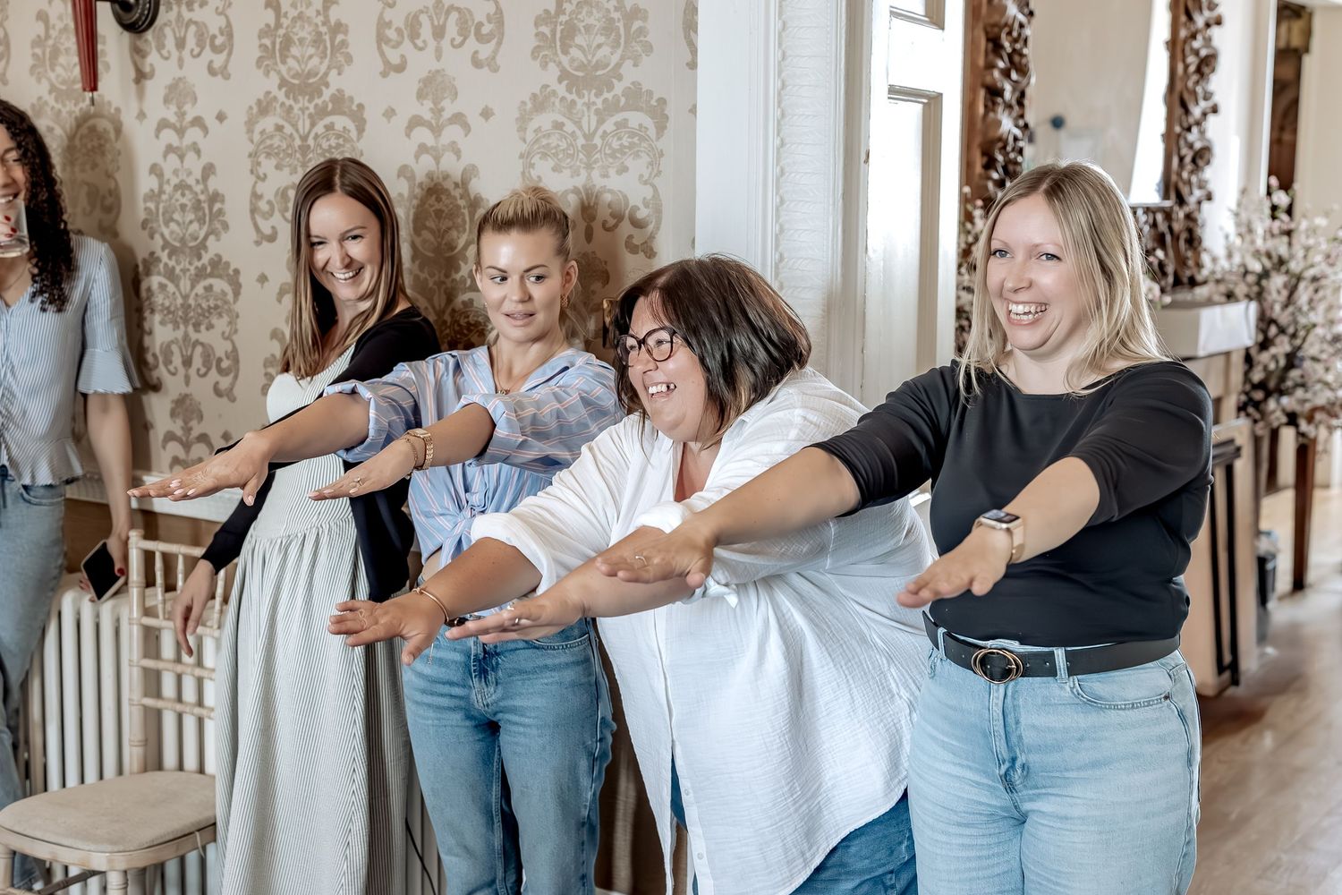 A group of people stretching their arms out in a bright interior room.
