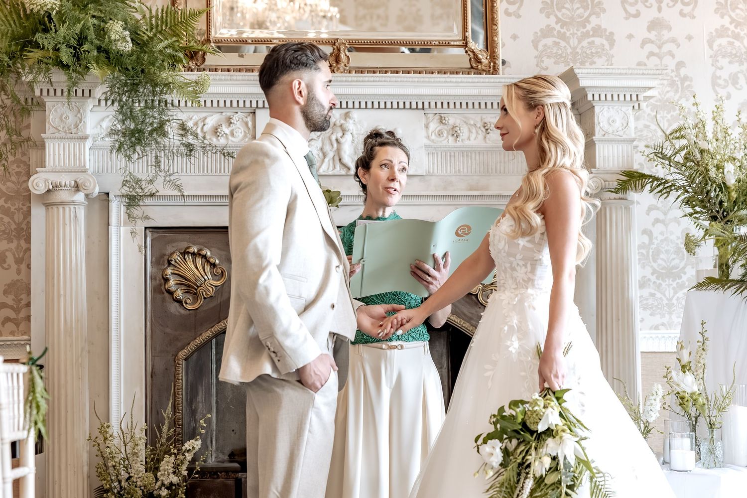Elegant wedding scene in white with bride and groom sharing romantic moments in an ornate grand ballroom.