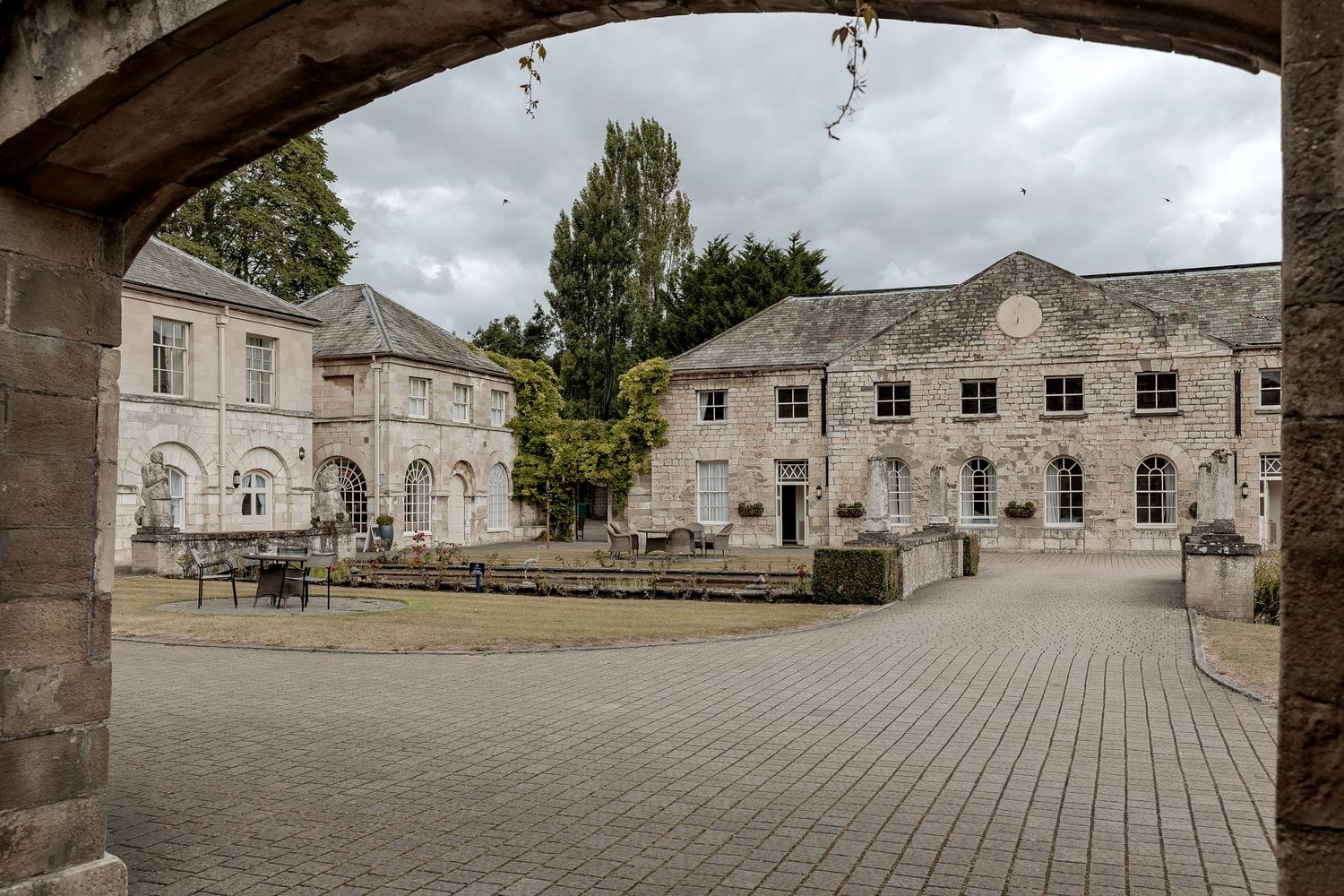 Historic stone courtyard with cobblestones and fountain viewed through an archway at a Yorkshire castle.