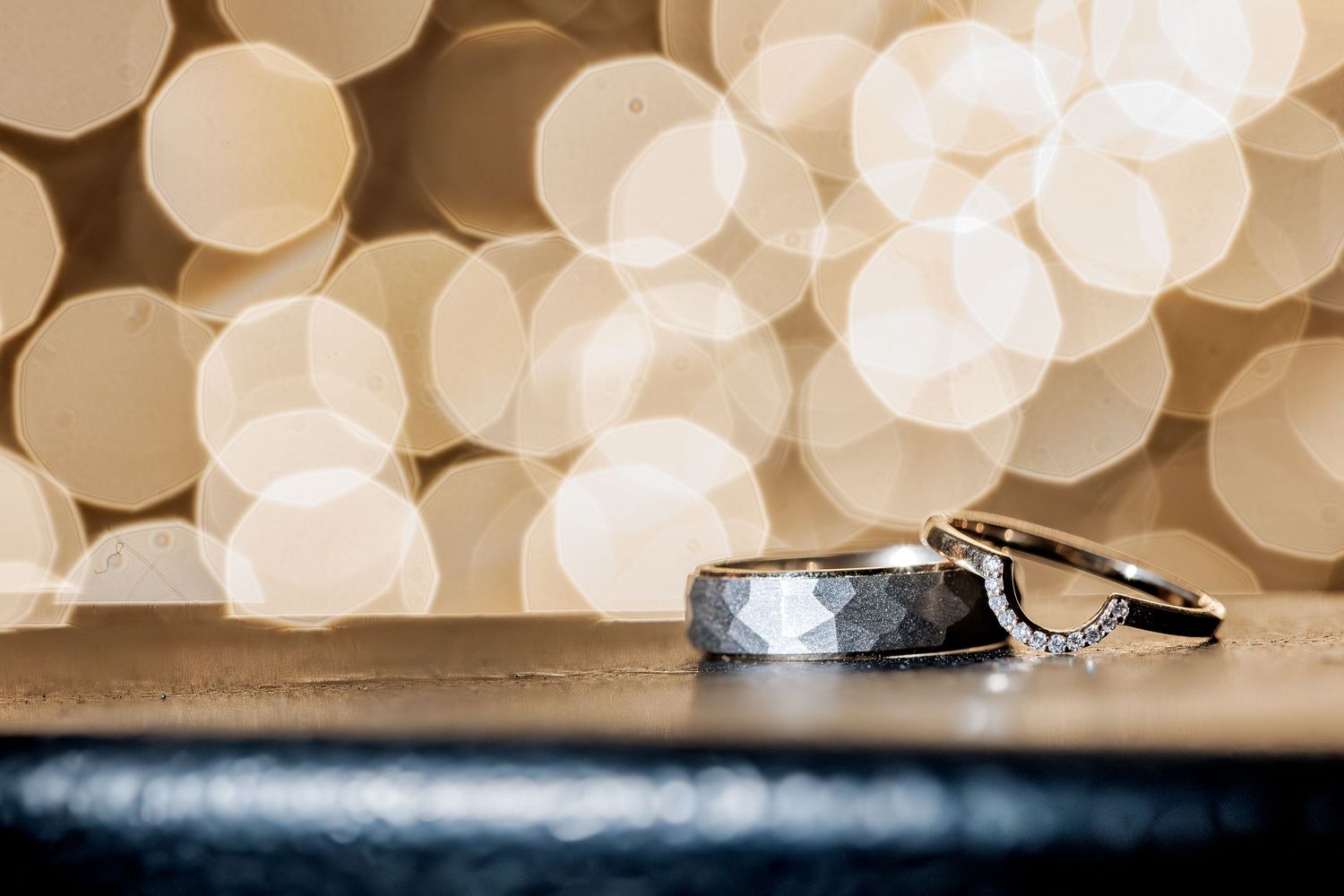 2 wedding rings positioned with bokeh behind from lights to showcase wedding rings on wedding day.