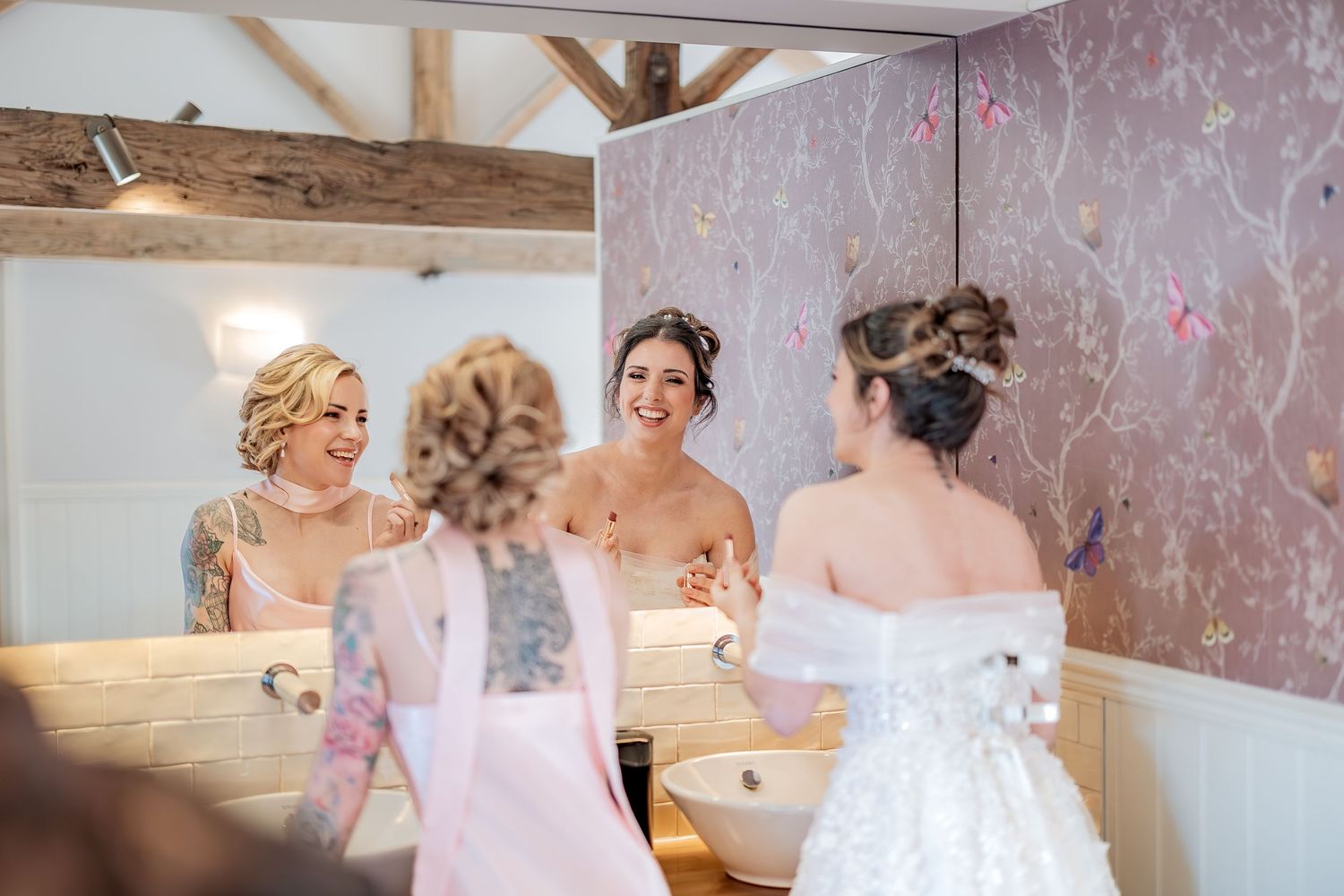 Bride and bridesmaid share a joke in their wedding venues bathroom.