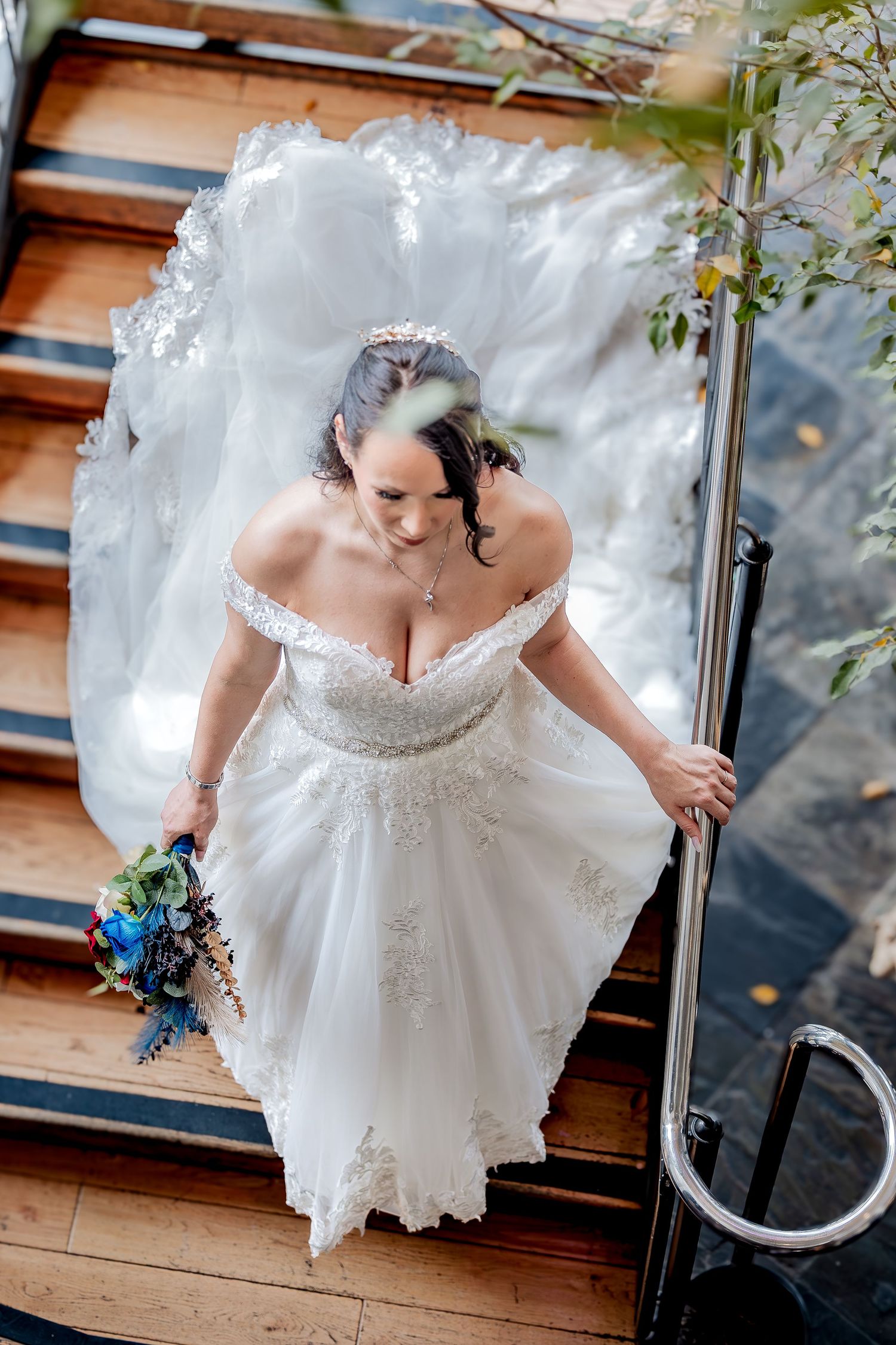A bride in a white lace wedding dress poses gracefully on wooden stairs in a series of artistic shots.