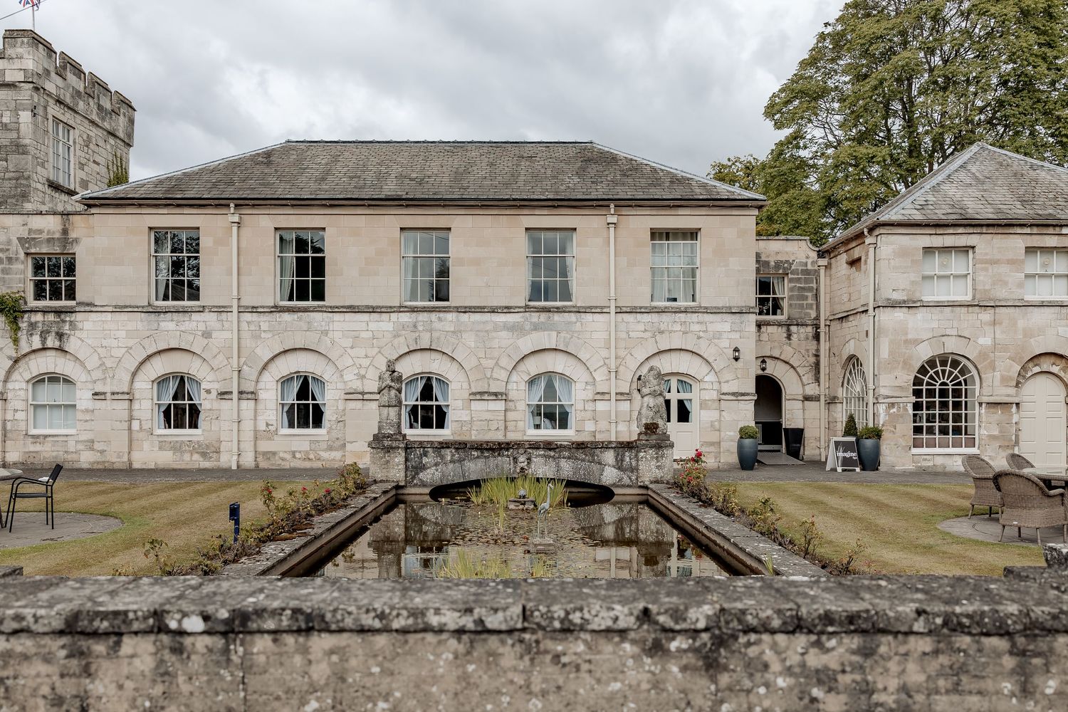 Classical Georgian stone building with arched windows and stone courtyard walls at an historic estate.