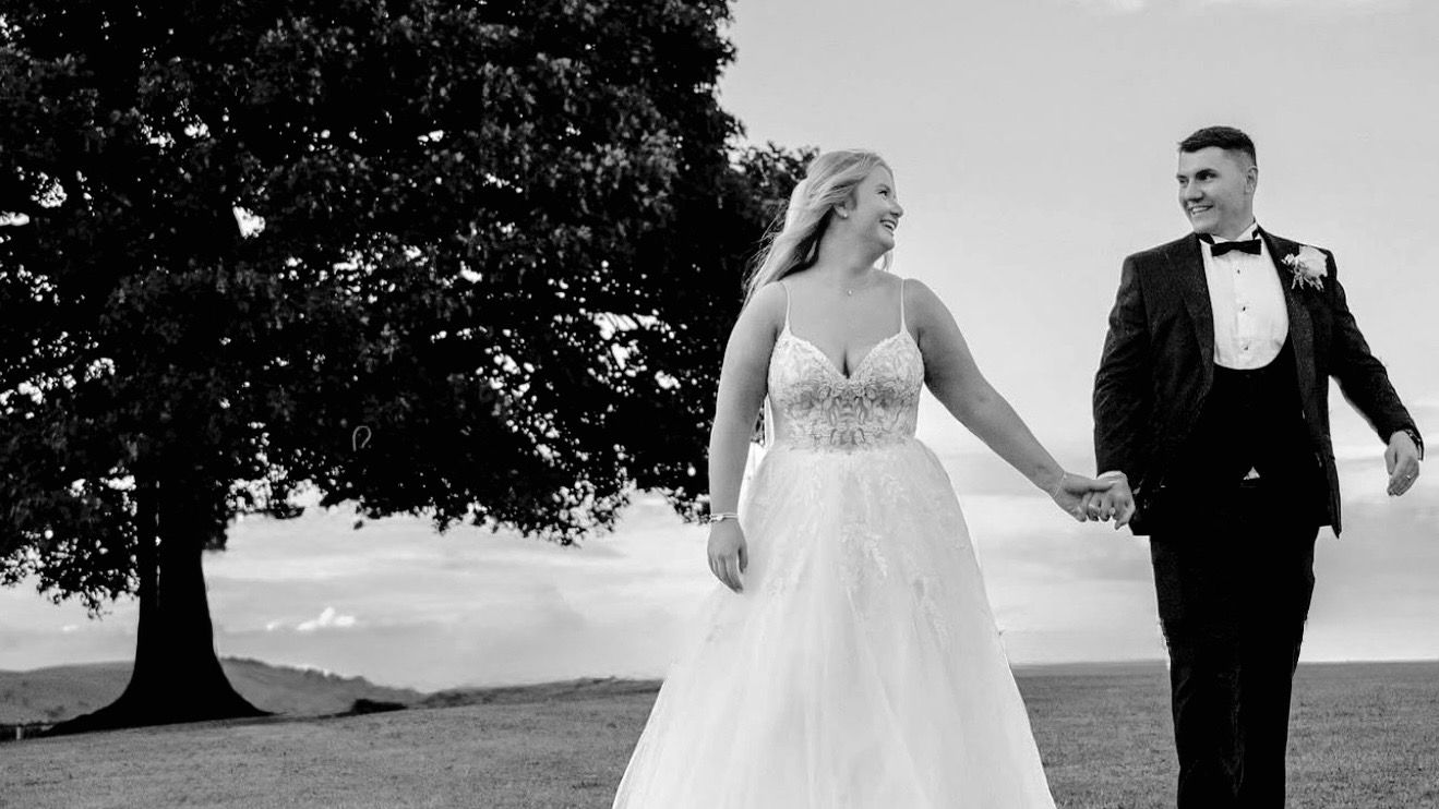 A black and white panoramic wedding photo collage showing romantic moments between newlyweds in a field at their wedding venue