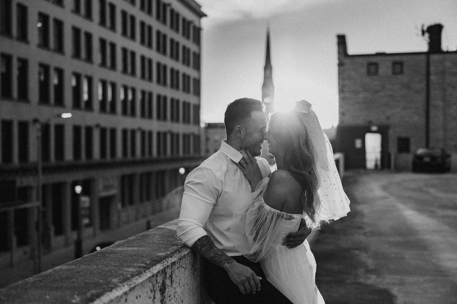 Engaged couple on the rooftop in Joliet, Illinois with a sunset sun burst in black and white