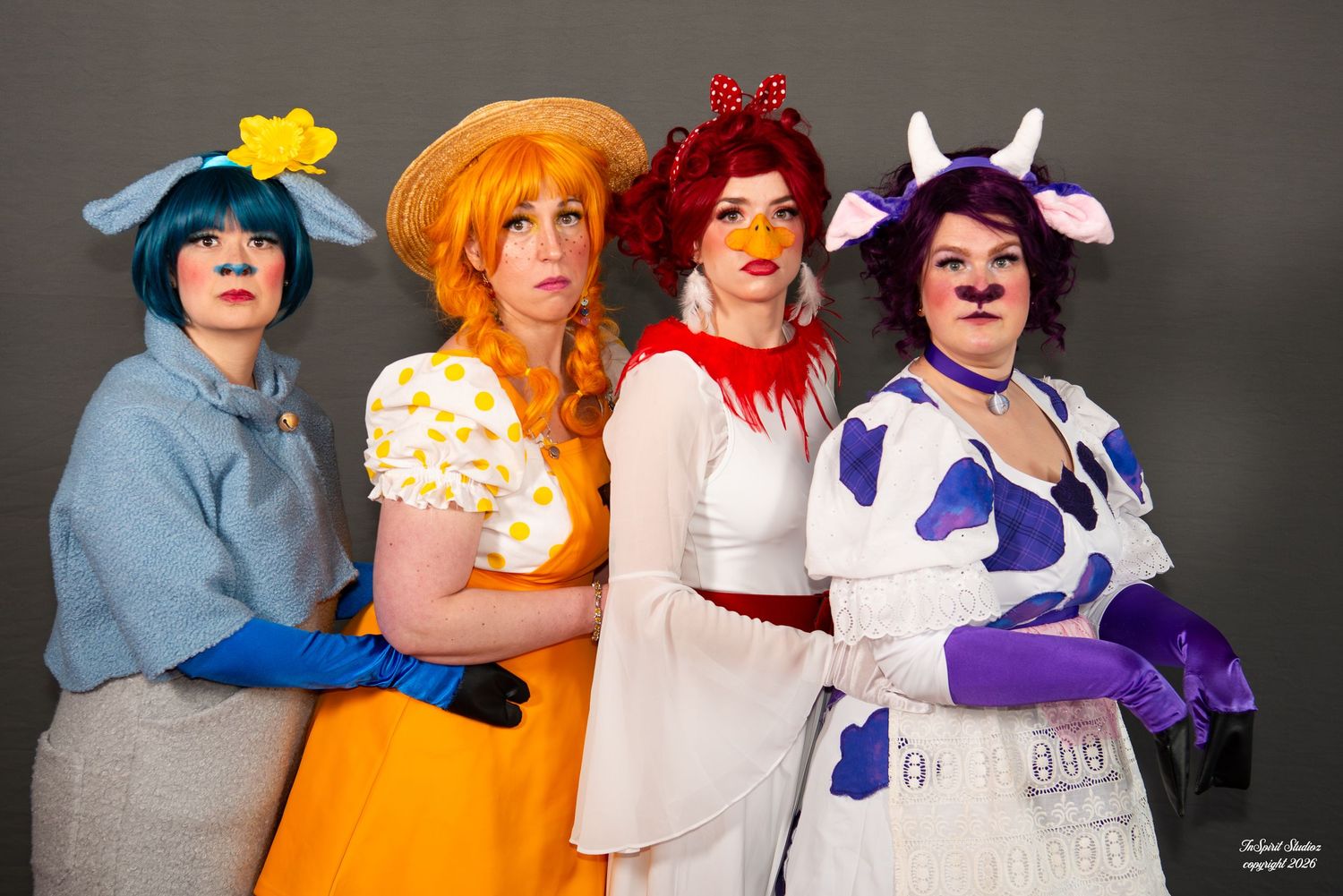 Four women in colorful cow-themed cosplay costumes posing together at an event.