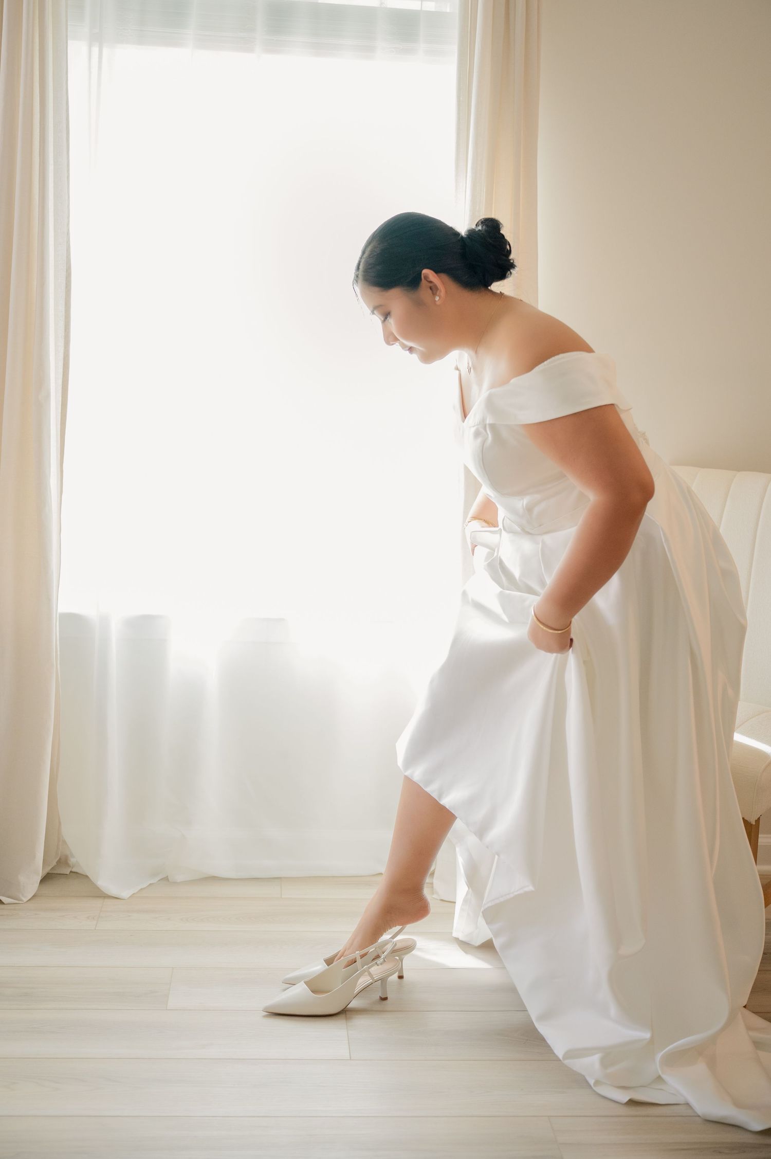 Minimalist bridal portraits in white dress against light window background.