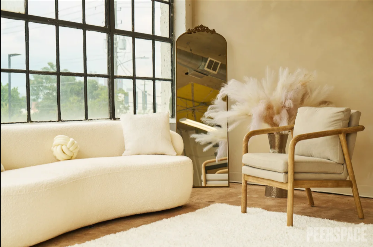 Luxurious living room with cream colored furniture and large windows creating natural lighting.