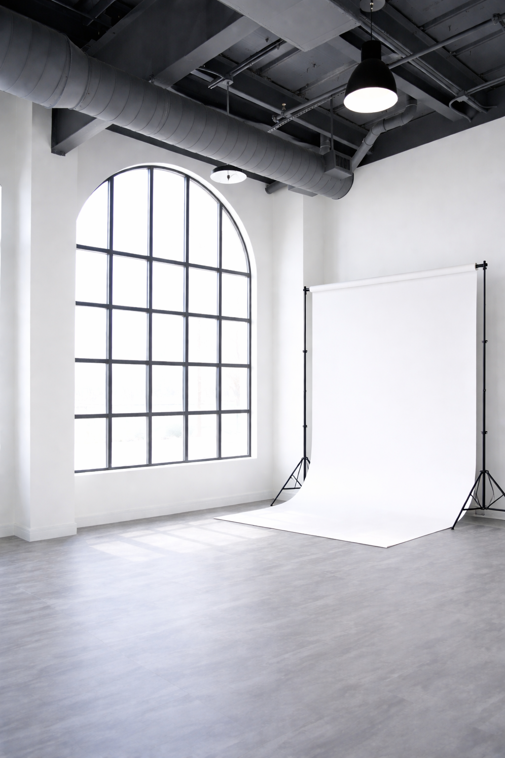 Minimalist white photo studio interior with industrial windows and high ceilings.