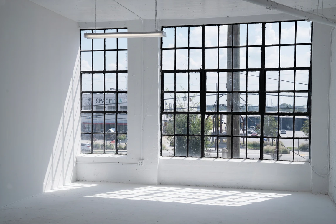 Modern industrial studio space with large windows and exposed ceiling creating natural lighting.