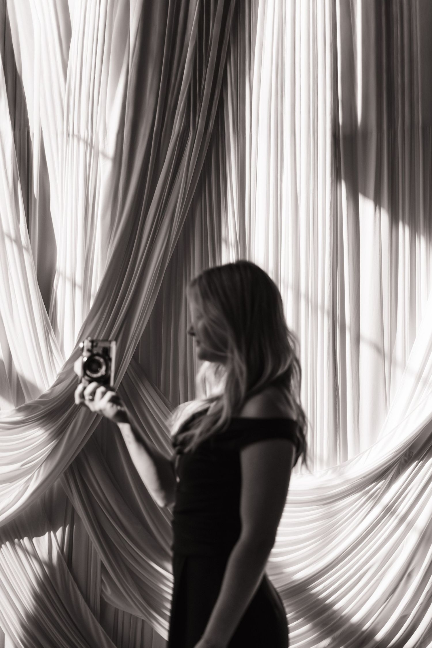 Artistic black and white portrait series with flowing white curtain backdrop.