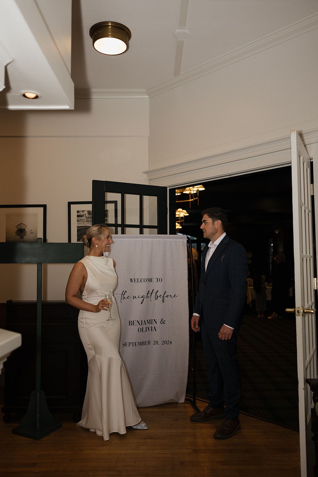 A couple shares a first look moment in a hallway with a welcome sign visible in the background.