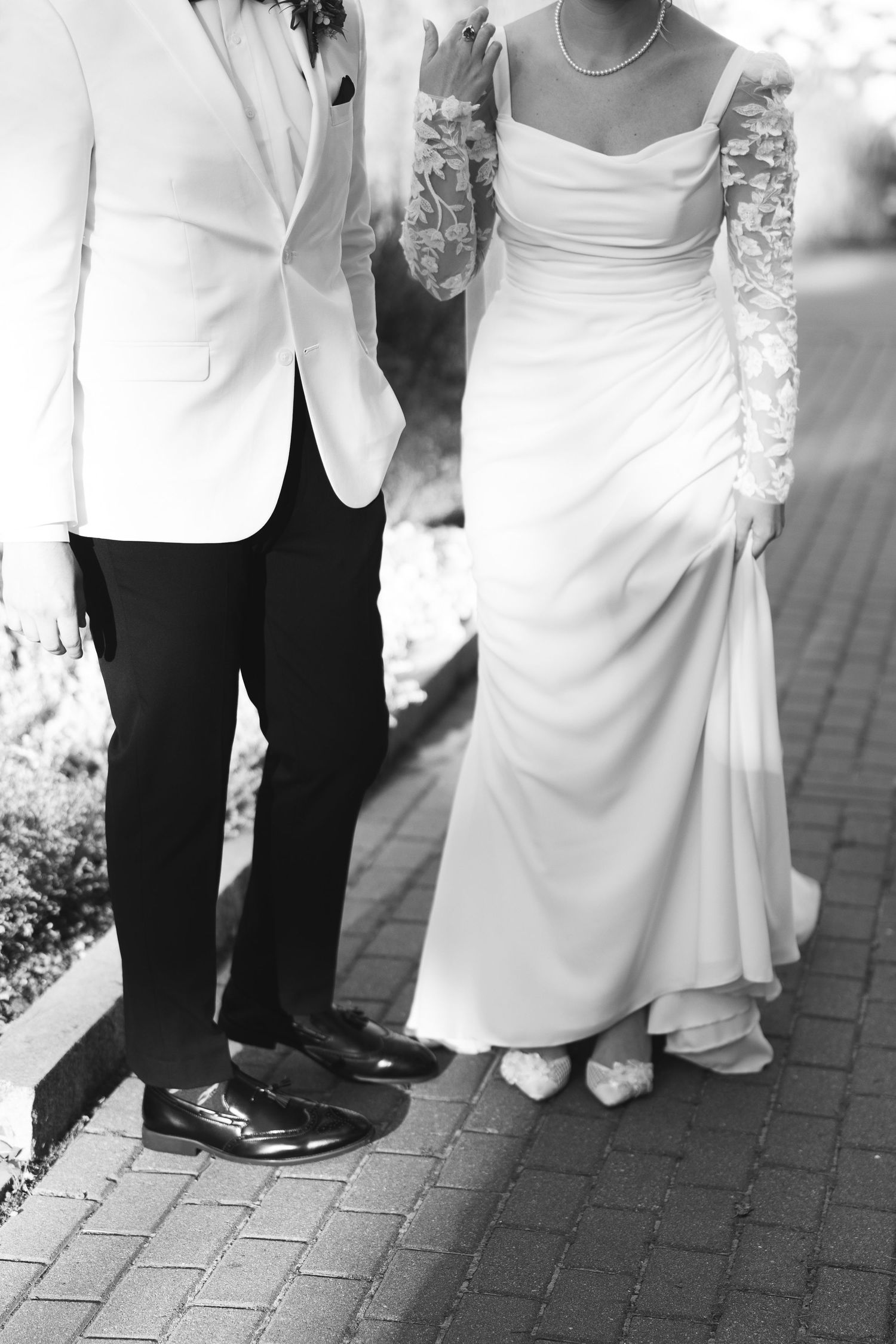 Black and white wedding photo series showing close-up details of feet and formal attire on brick pavement.