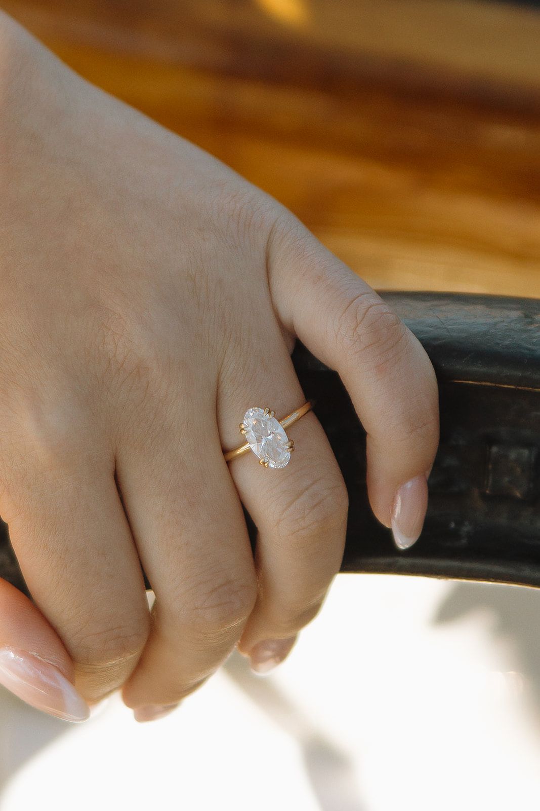 A close-up sequence of photos showing a sparkling diamond engagement ring on a hand against a warm wooden background.