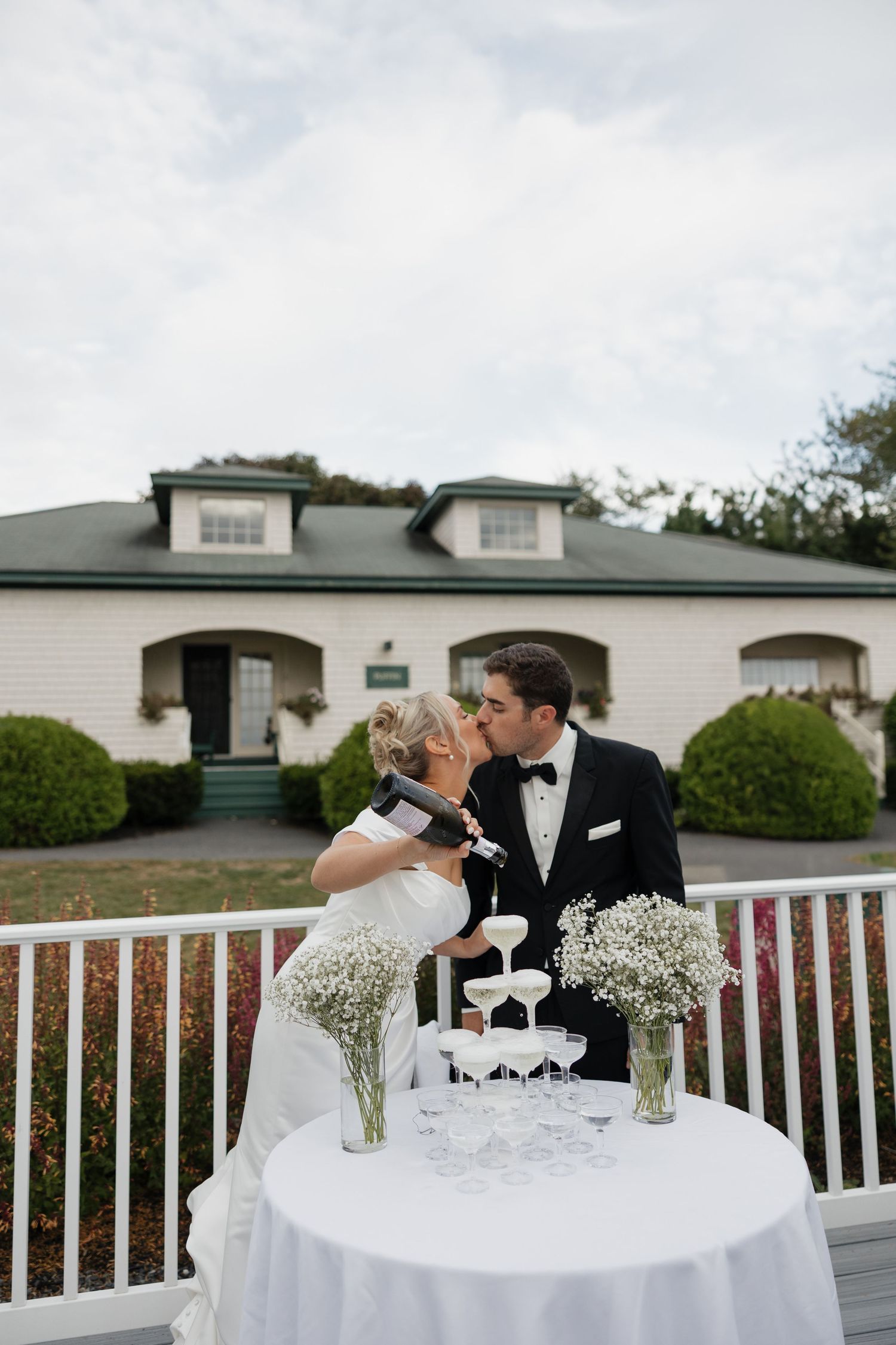A romantic sequence shows a couple sharing intimate moments at a white-railed outdoor venue with baby's breath centerpieces.